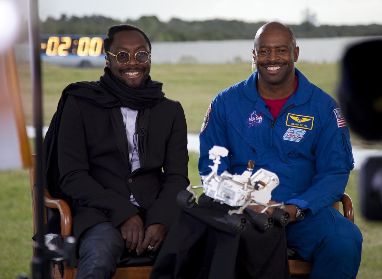 CAPE CANAVERAL, Fla. – Will.i.am, left, entertainer and member of The Black Eyed Peas, and former astronaut Leland Melvin, NASA associate administrator for Education, take part in a Tweetup at NASA Kennedy Space Center's Press Site in Florida during prelaunch activities for the agency’s Mars Science Laboratory (MSL) launch.  Behind them glint the lights of the launch countdown clock.  Participants in the Tweetup are given the opportunity to listen to agency briefings, tour locations on the center normally off limits to visitors, and get a close-up view of Space Launch Complex-41 on Cape Canaveral Air Force Station. The tweeters will share their experiences with followers through the social networking site Twitter. The MSL mission will pioneer precision landing technology and a sky-crane touchdown to place a car-sized rover, Curiosity, near the foot of a mountain inside Gale Crater on Aug. 6, 2012. During a nearly two-year prime mission after landing, the rover will investigate whether the region has ever offered conditions favorable for microbial life, including the chemical ingredients for life.  Liftoff of MSL aboard a United Launch Alliance Atlas V rocket from pad 41 is planned during a launch window which extends from 10:02 a.m. to 11:45 a.m. EST on Nov. 26. For more information, visit http://www.nasa.gov/msl. Photo credit: NASA/Frankie Martin