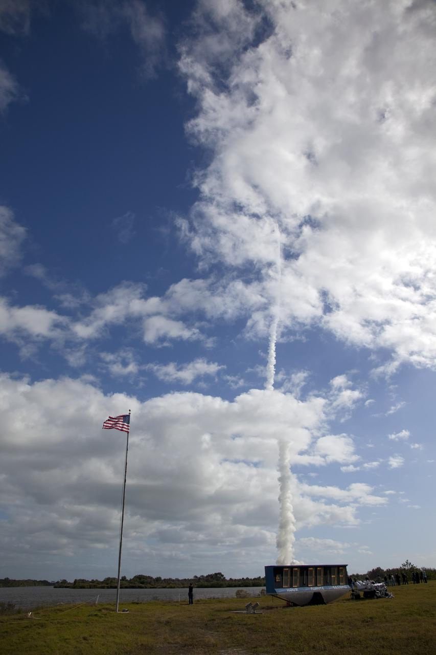 CAPE CANAVERAL, Fla. – At NASA Kennedy Space Center's Press Site in Florida, a U.S. flag flaps in the breeze next to the countdown clock at the turn basin. Overhead, the contrail of the United Launch Alliance Atlas V rocket, carrying the agency's Mars Science Laboratory (MSL) into space, dissects the clouds over Space Launch Complex-41 on neighboring Cape Canaveral Air Force Station.  Liftoff came at 10:02 a.m. EST at the opening of the launch window.    MSL's components include a car-sized rover, Curiosity, which has 10 science instruments designed to search for signs of life, including methane, and help determine if the gas is from a biological or geological source. For more information, visit http://www.nasa.gov/msl. Photo credit: NASA/Frankie Martin