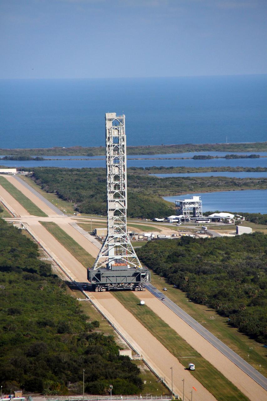 CAPE CANAVERAL, Fla. – The mobile launcher, or ML, passes by the Launch Complex 39 Observation Gantry at NASA's Kennedy Space Center in Florida as it makes the 4.2-mile trek from Launch Pad 39B to the park site near the Vehicle Assembly Building.  In the background is the Atlantic Ocean.    Data on the ML collected from structural and functional engineering tests during its two-week stay on the pad will be used in the next phases of construction. The 355-foot-tall ML structure, which took about two years to construct, will be modified by NASA’s 21st Century Ground Systems Program to support NASA’s Space Launch System, the heavy-lift rocket that will launch astronauts into deep space on future exploration missions. For more information, visit http://www.nasa.gov/exploration/systems/sls. Photo credit: NASA/Cory Huston