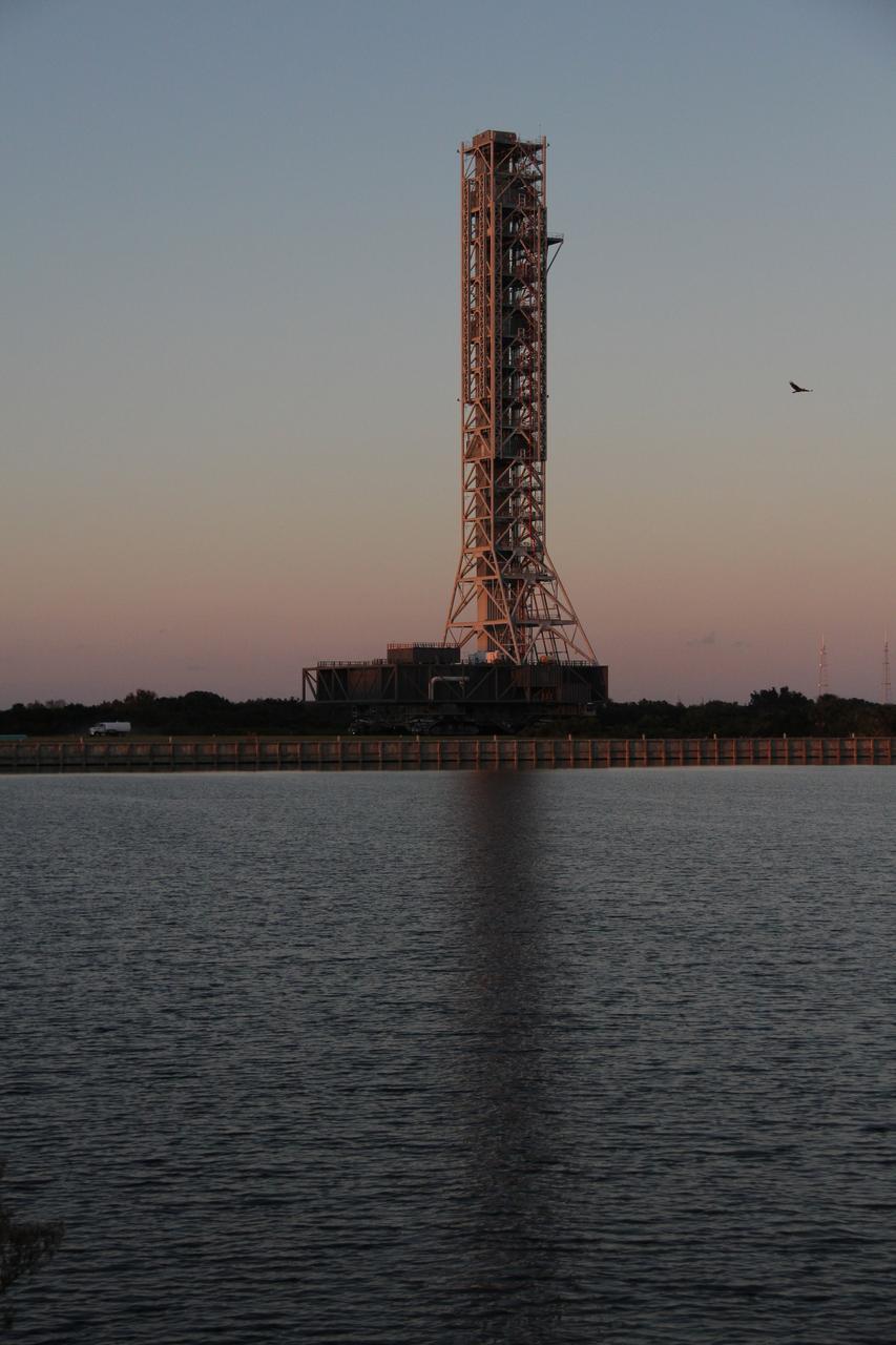 CAPE CANAVERAL, Fla. – The sun sets behind the mobile launcher, or ML, as it makes its way past the turn basin at NASA's Kennedy Space Center in Florida. The ML is nearing the end of its 4.2-mile trek from Launch Pad 39B to the park site near the Vehicle Assembly Building.     Data on the ML collected from structural and functional engineering tests during its two-week stay on the pad will be used in the next phases of construction. The 355-foot-tall ML structure, which took about two years to construct, will be modified by NASA’s 21st Century Ground Systems Program to support NASA’s Space Launch System, the heavy-lift rocket that will launch astronauts into deep space on future exploration missions. For more information, visit http://www.nasa.gov/exploration/systems/sls. Photo credit: NASA/Cory Huston