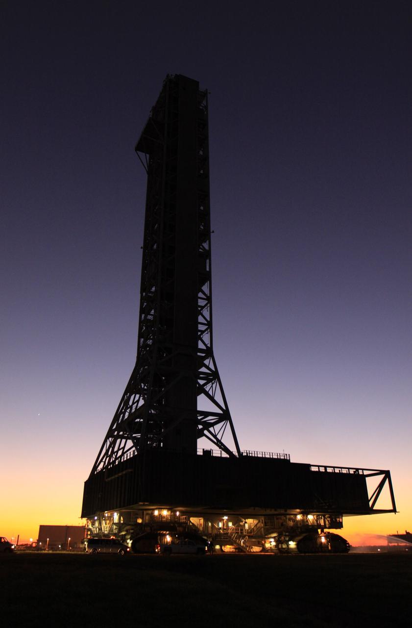 CAPE CANAVERAL, Fla. – As night falls at NASA's Kennedy Space Center in Florida, the mobile launcher, or ML, nears the park site outside the Vehicle Assembly Building.  The ML is coming to the end of its 4.2-mile, day-long trek from Launch Pad 39B.     Data on the ML collected from structural and functional engineering tests during its two-week stay on the pad will be used in the next phases of construction. The 355-foot-tall ML structure, which took about two years to construct, will be modified by NASA’s 21st Century Ground Systems Program to support NASA’s Space Launch System, the heavy-lift rocket that will launch astronauts into deep space on future exploration missions. For more information, visit http://www.nasa.gov/exploration/systems/sls. Photo credit: NASA/Kim Shiflett