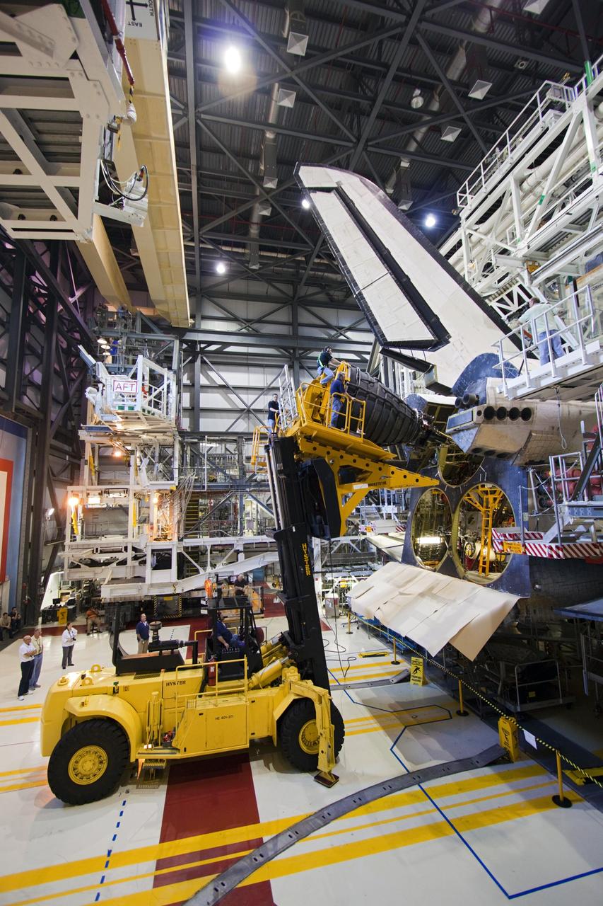 CAPE CANAVERAL, Fla. – Inside Orbiter Processing Facility-1 at NASA's Kennedy Space Center in Florida, a lift holds a replica shuttle main engine (RSME) for installation on space shuttle Discovery.     This is the first of three replica engines to be installed. The work is part of the Space Shuttle Program’s transition and retirement processing of Discovery. Discovery is being prepared for display at the Smithsonian’s National Air and Space Museum, Steven F. Udvar-Hazy Center in Chantilly, Va. For more information, visit http://www.nasa.gov/shuttle.  Photo credit: NASA/Jim Grossmann
