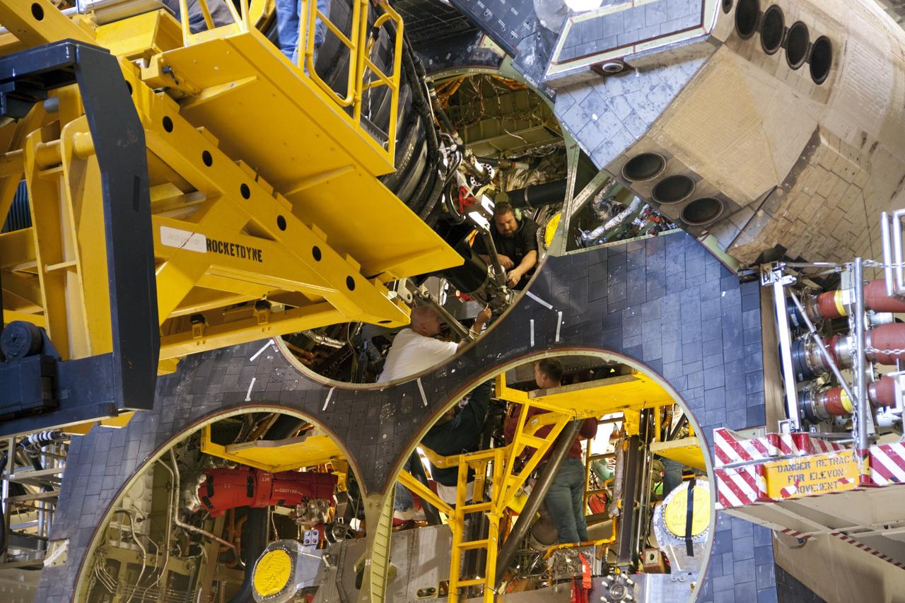 CAPE CANAVERAL, Fla. – Inside Orbiter Processing Facility-1 at NASA's Kennedy Space Center in Florida, employees work within the aft end of space shuttle Discovery, where a replica shuttle main engine (RSME) is being installed.    This is the first of three replica engines to be installed. The work is part of the Space Shuttle Program’s transition and retirement processing of Discovery. Discovery is being prepared for display at the Smithsonian’s National Air and Space Museum, Steven F. Udvar-Hazy Center in Chantilly, Va. For more information, visit http://www.nasa.gov/shuttle.  Photo credit: NASA/Jim Grossmann