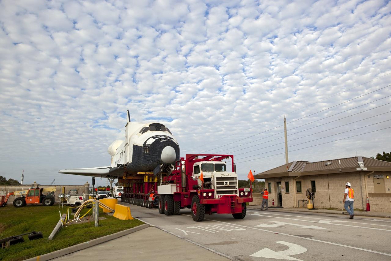 CAPE CANAVERAL, Fla. – The transporter carrying the high-fidelity space shuttle model that was on display at the NASA Kennedy Space Center Visitor Complex in Florida rolls past a security gate at the center.  The model is being moved from the visitor complex to NASA Kennedy Space Center's Launch Complex 39 turn basin.  The shuttle was part of a display at the visitor complex that also included an external tank and two solid rocket boosters that were used to show visitors the size of actual space shuttle components. The full-scale shuttle model is being transferred from Kennedy to Space Center Houston, NASA Johnson Space Center's visitor center. The model will stay at the turn basin for a few months until it is ready to be transported to Texas via barge. The move also helps clear the way for the Kennedy Space Center Visitor Complex to begin construction of a new facility next year to display space shuttle Atlantis in 2013.  For more information about Space Center Houston, visit http://www.spacecenter.org.  Photo credit: NASA/Dimitri Gerondidakis