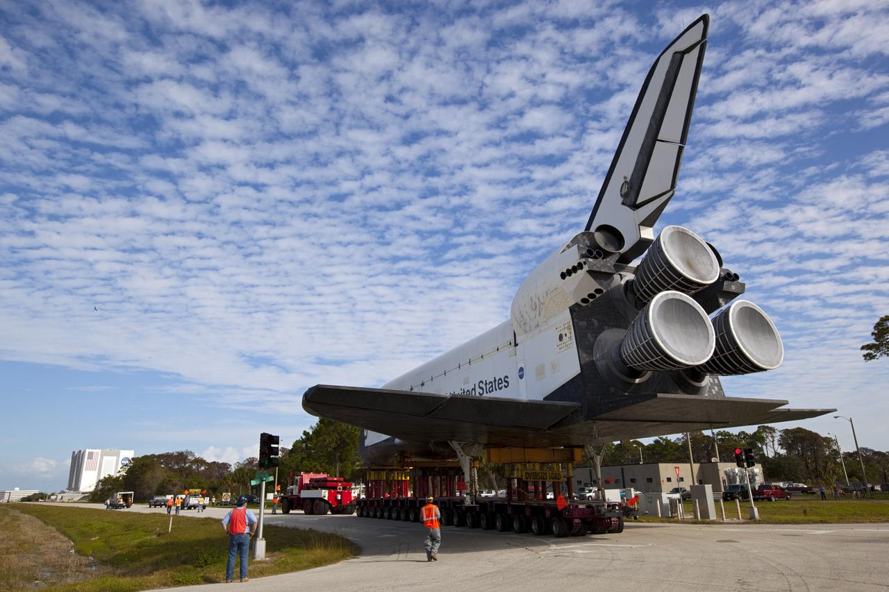 CAPE CANAVERAL, Fla. – The high-fidelity space shuttle model which was on display at the NASA Kennedy Space Center Visitor Complex in Florida travels down Contractor Road on its way to Kennedy's Launch Complex 39 turn basin.  In the distance is the 525-foot-tall Vehicle Assembly Building.    The shuttle was part of a display at the visitor complex that also included an external tank and two solid rocket boosters that were used to show visitors the size of actual space shuttle components. The full-scale shuttle model is being transferred from Kennedy to Space Center Houston, NASA Johnson Space Center's visitor center. The model will stay at the turn basin for a few months until it is ready to be transported to Texas via barge. The move also helps clear the way for the Kennedy Space Center Visitor Complex to begin construction of a new facility next year to display space shuttle Atlantis in 2013.  For more information about Space Center Houston, visit http://www.spacecenter.org.  Photo credit: NASA/Dimitri Gerondidakis