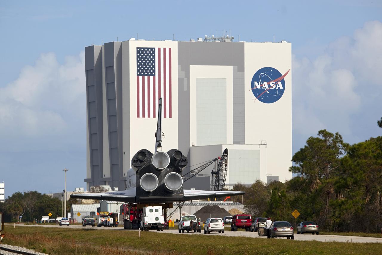 CAPE CANAVERAL, Fla. – The high-fidelity space shuttle model which was on display at the NASA Kennedy Space Center Visitor Complex in Florida approaches the 525-foot-tall Vehicle Assembly Building as it makes its way to Kennedy's Launch Complex 39 turn basin.     The shuttle was part of a display at the visitor complex that also included an external tank and two solid rocket boosters that were used to show visitors the size of actual space shuttle components. The full-scale shuttle model is being transferred from Kennedy to Space Center Houston, NASA Johnson Space Center's visitor center. The model will stay at the turn basin for a few months until it is ready to be transported to Texas via barge. The move also helps clear the way for the Kennedy Space Center Visitor Complex to begin construction of a new facility next year to display space shuttle Atlantis in 2013.  For more information about Space Center Houston, visit http://www.spacecenter.org.  Photo credit: NASA/Dimitri Gerondidakis