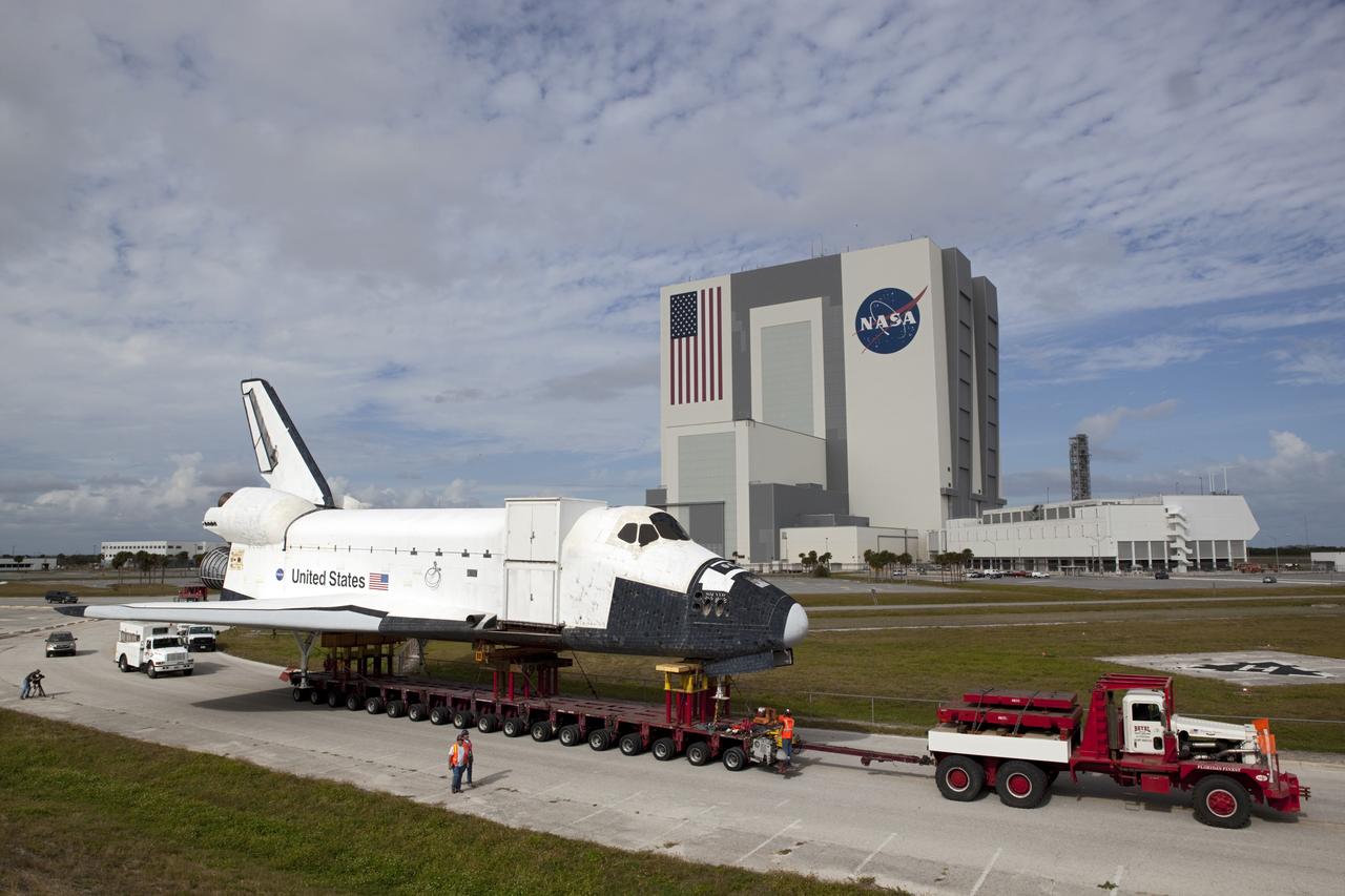CAPE CANAVERAL, Fla. – The high-fidelity space shuttle model which was on display at the NASA Kennedy Space Center Visitor Complex in Florida rolls through the parking lot leading to Kennedy's Launch Complex 39 turn basin.  Behind it are the 525-foot-tall Vehicle Assembly Building and the Launch Control Center.     The shuttle was part of a display at the visitor complex that also included an external tank and two solid rocket boosters that were used to show visitors the size of actual space shuttle components. The full-scale shuttle model is being transferred from Kennedy to Space Center Houston, NASA Johnson Space Center's visitor center. The model will stay at the turn basin for a few months until it is ready to be transported to Texas via barge. The move also helps clear the way for the Kennedy Space Center Visitor Complex to begin construction of a new facility next year to display space shuttle Atlantis in 2013.  For more information about Space Center Houston, visit http://www.spacecenter.org.  Photo credit: NASA/Dimitri Gerondidakis
