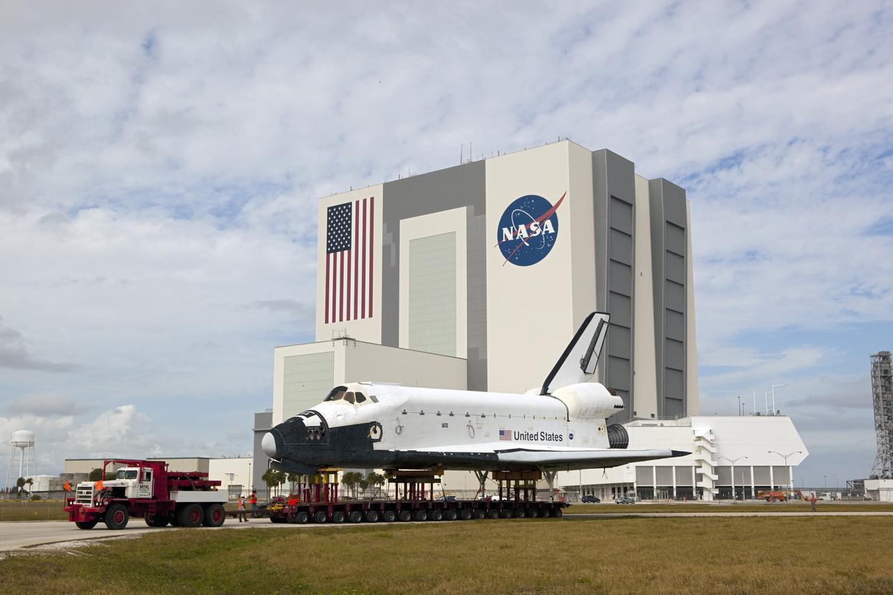 CAPE CANAVERAL, Fla. – The high-fidelity space shuttle model which was on display at the NASA Kennedy Space Center Visitor Complex in Florida rolls through the Press Site parking lot toward Kennedy's Launch Complex 39 turn basin.  Behind it, the Vehicle Assembly Building towers 525 feet in the air.     The shuttle was part of a display at the visitor complex that also included an external tank and two solid rocket boosters that were used to show visitors the size of actual space shuttle components. The full-scale shuttle model is being transferred from Kennedy to Space Center Houston, NASA Johnson Space Center's visitor center. The model will stay at the turn basin for a few months until it is ready to be transported to Texas via barge. The move also helps clear the way for the Kennedy Space Center Visitor Complex to begin construction of a new facility next year to display space shuttle Atlantis in 2013.  For more information about Space Center Houston, visit http://www.spacecenter.org.  Photo credit: NASA/Dimitri Gerondidakis