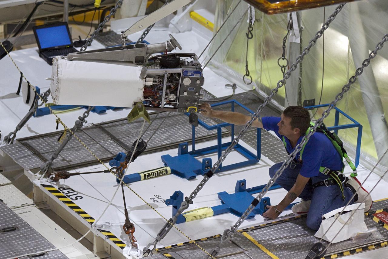 CAPE CANAVERAL, Fla. – Inside Orbiter Processing Facility-2 at NASA’s Kennedy Space Center in Florida, a technician assists as a special crane lifts one of the three fuel cells away from space shuttle Atlantis’ payload bay.    The fuel cells will be drained of all fluids. The hydrogen and oxygen dewars which feed reactants to the fuel cells remain in Atlantis’ mid-body and will be purged with inert gases and vented down. The work is part of the Space Shuttle Program’s transition and retirement processing of shuttle Atlantis. The orbiter is being prepared for display at the Kennedy Space Center Visitor Complex.  Photo credit: NASA/Kim Shiflett