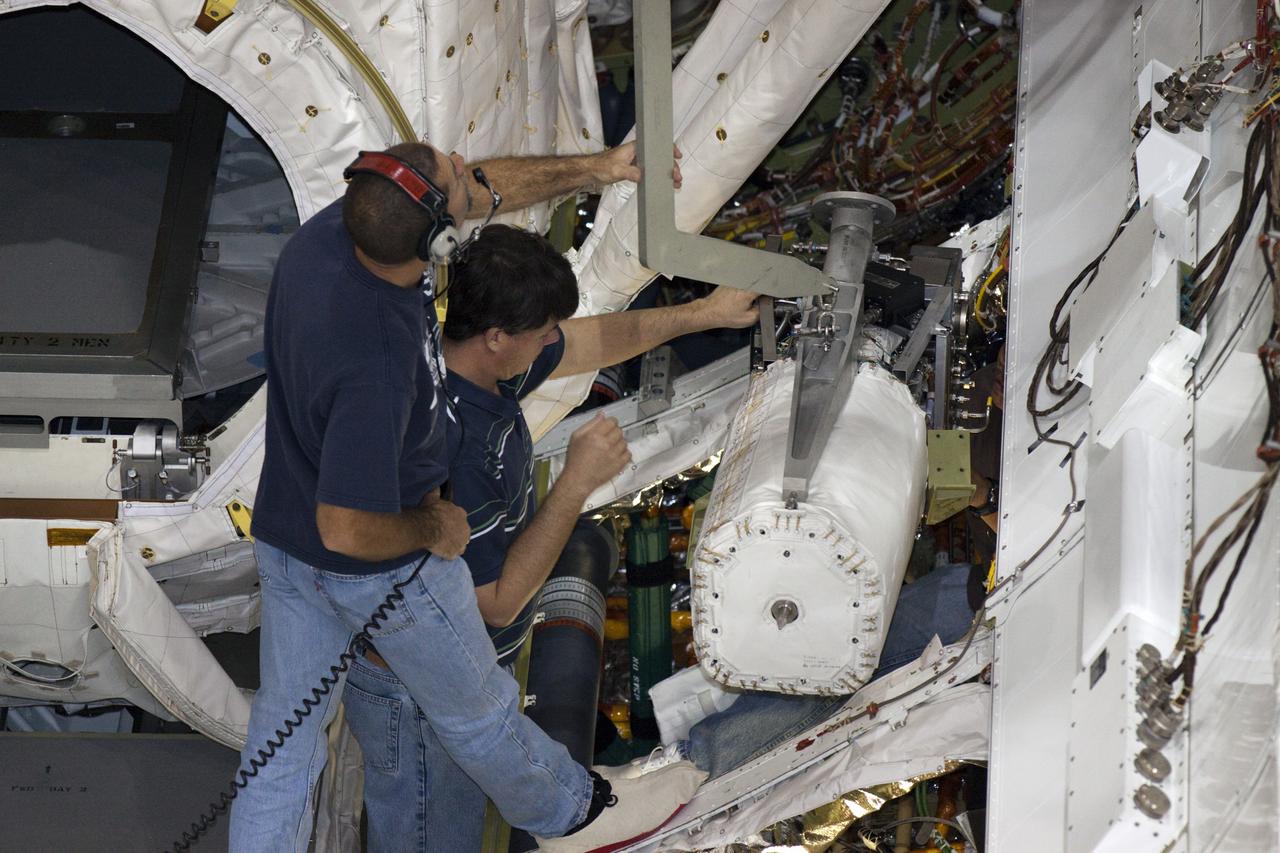 CAPE CANAVERAL, Fla. – Inside Orbiter Processing Facility-2 at NASA’s Kennedy Space Center in Florida, technicians assist as a special crane is used to lift one of the three fuel cells away from space shuttle Atlantis’ payload bay.    The fuel cells will be drained of all fluids. The hydrogen and oxygen dewars which feed reactants to the fuel cells remain in Atlantis’ mid-body and will be purged with inert gases and vented down. The work is part of the Space Shuttle Program’s transition and retirement processing of shuttle Atlantis. The orbiter is being prepared for display at the Kennedy Space Center Visitor Complex.  Photo credit: NASA/Kim Shiflett