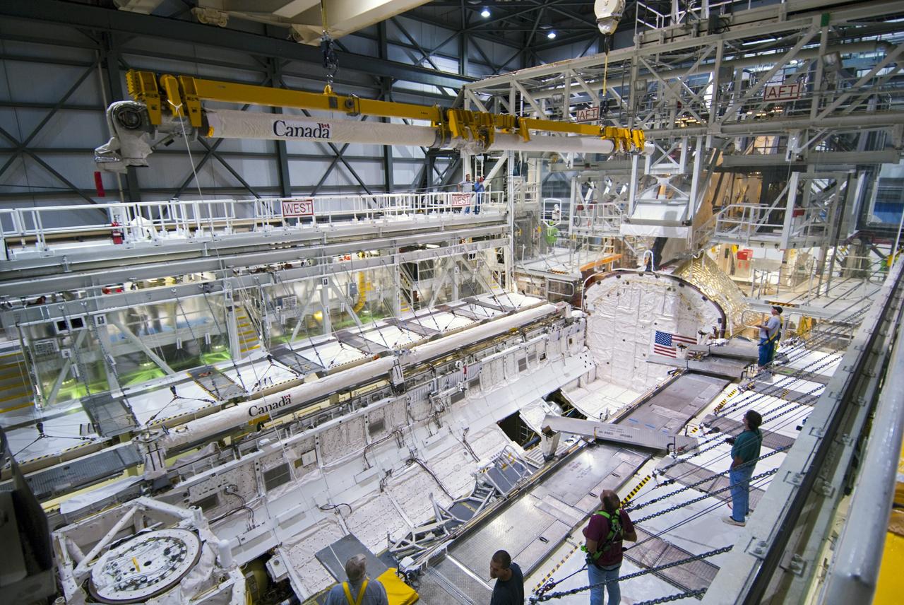 CAPE CANAVERAL, Fla. – Inside Orbiter Processing Facility-2 at NASA’s Kennedy Space Center in Florida, technicians monitor the progress as a large crane lifts the remote manipulator system (RMS) robotic arm high above space shuttle Atlantis’ payload bay.     The RMS will be transported to NASA’s Johnson Space Center in Houston for possible use on future spaceflights. The work is part of the Space Shuttle Program’s transition and retirement processing of shuttle Atlantis. The shuttle is being prepared for display at the Kennedy Space Center Visitor Complex.  Photo credit: NASA/Jim Grossmann
