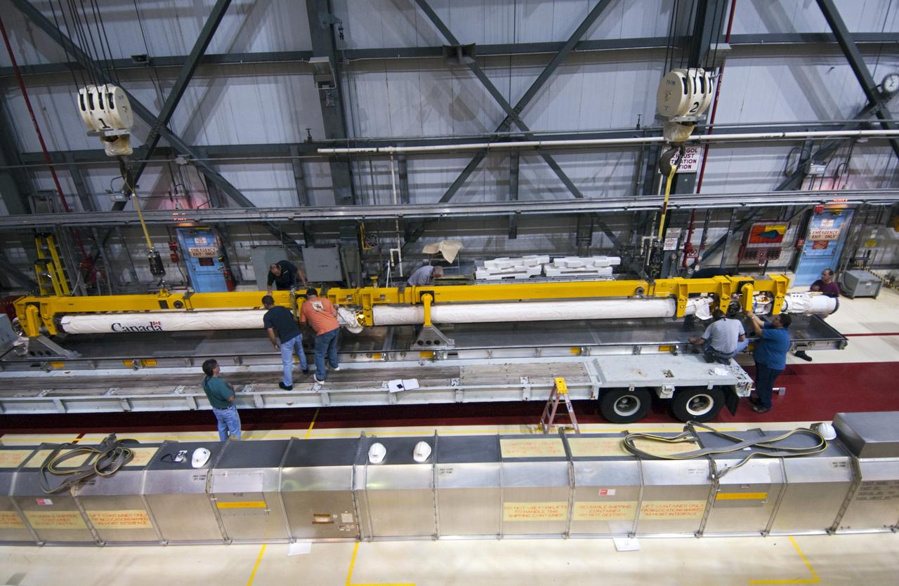CAPE CANAVERAL, Fla. – Inside Orbiter Processing Facility-2 at NASA’s Kennedy Space Center in Florida, technicians assist as a large crane lowers space shuttle Atlantis’ remote manipulator system (RMS) robotic arm onto a special carrier platform.    The RMS will be transported to NASA’s Johnson Space Center in Houston for possible use on future spaceflights. The work is part of the Space Shuttle Program’s transition and retirement processing of shuttle Atlantis. The shuttle is being prepared for display at the Kennedy Space Center Visitor Complex.  Photo credit: NASA/Jim Grossmann
