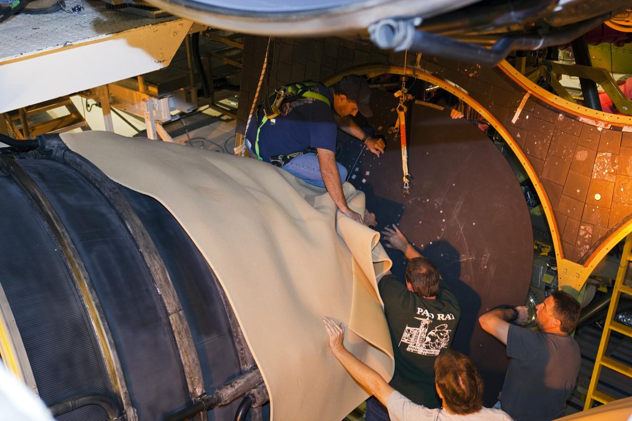 CAPE CANAVERAL, Fla. – Inside Orbiter Processing Facility-1 at NASA’s Kennedy Space Center in Florida, technicians help guide one of space shuttle Discovery’s replica shuttle main engines (RSME) into place after the eyelid and heat shield were installed. The heat shields are composed of two, semi-circle-shaped sections of thermal protection system tiles that surround the engines. The work is part of the Space Shuttle Program’s transition and retirement processing of shuttle Discovery. Discovery is being prepared for display at the Smithsonian’s National Air and Space Museum, Steven F. Udvar-Hazy Center in Chantilly, Va. For more information, visit http://www.nasa.gov/shuttle. Photo credit: NASA/Dimitri Gerondidakis