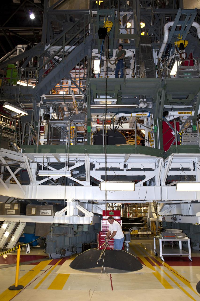 CAPE CANAVERAL, Fla. – Inside Orbiter Processing Facility-1 at NASA’s Kennedy Space Center in Florida, a technician attaches a crane to a heat shield that will be installed, along with an eyelid, on one of shuttle Discovery’s three replica shuttle main engines. The heat shields are composed of two, semi-circle-shaped sections of thermal protection system tiles that surround the engines. The work is part of the Space Shuttle Program’s transition and retirement processing of shuttle Discovery. Discovery is being prepared for display at the Smithsonian’s National Air and Space Museum, Steven F. Udvar-Hazy Center in Chantilly, Va. For more information, visit http://www.nasa.gov/shuttle. Photo credit: NASA/Dimitri Gerondidakis