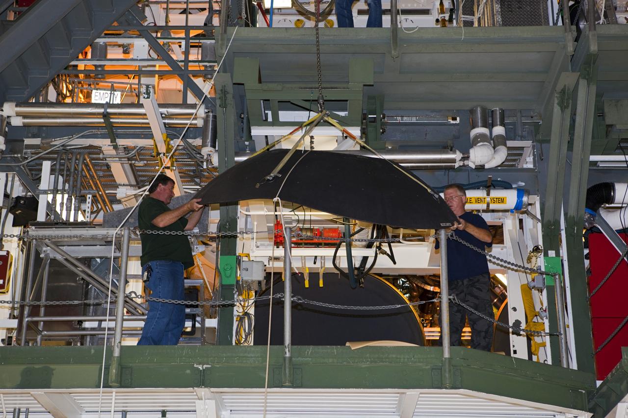 CAPE CANAVERAL, Fla. – Inside Orbiter Processing Facility-1 at NASA’s Kennedy Space Center in Florida, technicians help guide a heat shield attached to a crane. The heat shield, along with an eyelid, will be installed on one of shuttle Discovery’s three replica shuttle main engines. The heat shields are composed of two, semi-circle-shaped sections of thermal protection system tiles that surround the engines. The work is part of the Space Shuttle Program’s transition and retirement processing of shuttle Discovery. Discovery is being prepared for display at the Smithsonian’s National Air and Space Museum, Steven F. Udvar-Hazy Center in Chantilly, Va. For more information, visit http://www.nasa.gov/shuttle. Photo credit: NASA/Dimitri Gerondidakis