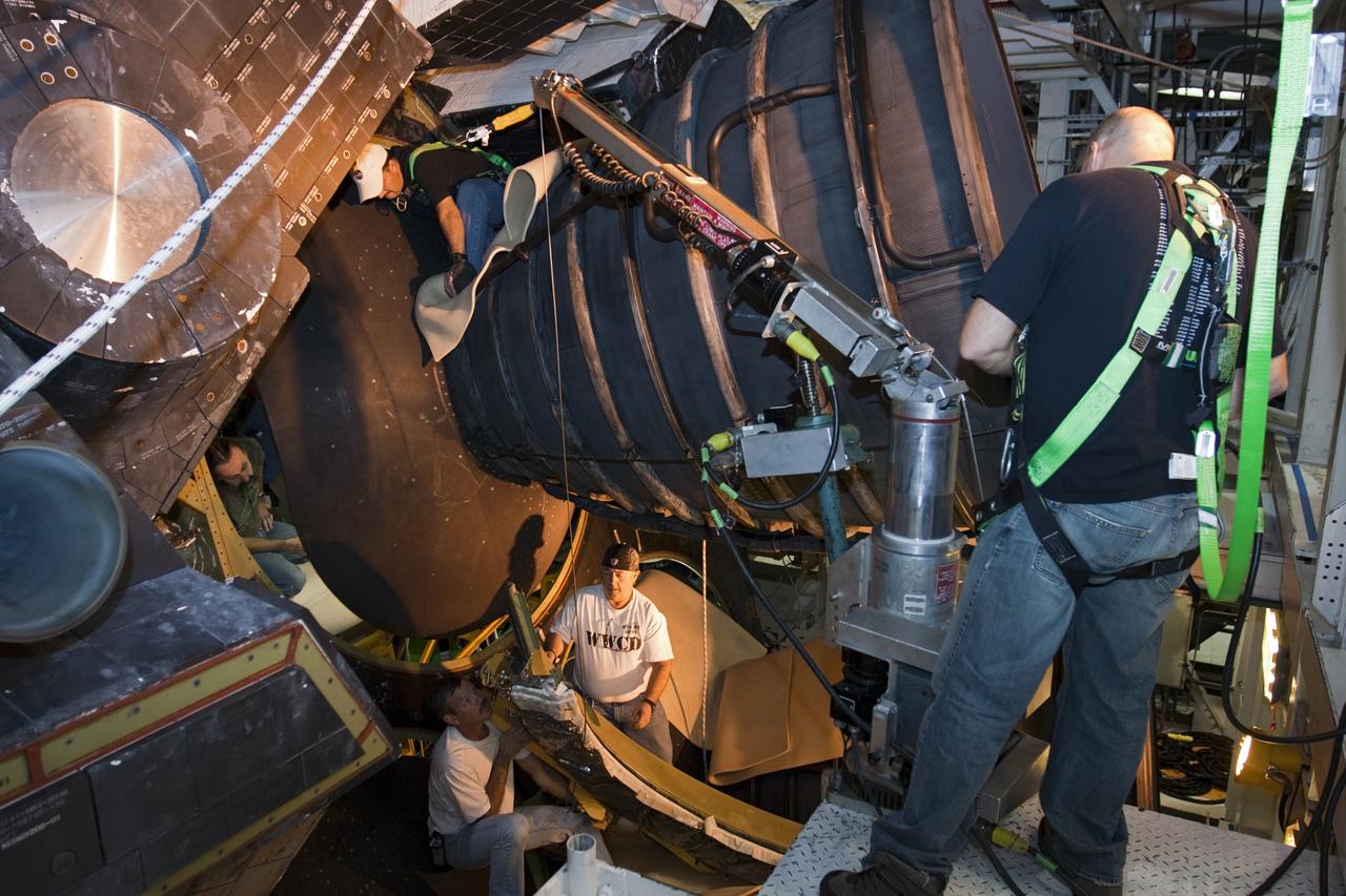 CAPE CANAVERAL, Fla. – Inside Orbiter Processing Facility-1 at NASA’s Kennedy Space Center in Florida, technicians help guide a dome heat shield for installation around one of space shuttle Discovery’s three replica shuttle main engines. The dome heat shields are composed of two, semi-circle-shaped sections of thermal protection system tiles that surround the engines. The work is part of the Space Shuttle Program’s transition and retirement processing of shuttle Discovery. Discovery is being prepared for display at the Smithsonian’s National Air and Space Museum, Steven F. Udvar-Hazy Center in Chantilly, Va. For more information, visit http://www.nasa.gov/shuttle. Photo credit: NASA/Kim Shiflett
