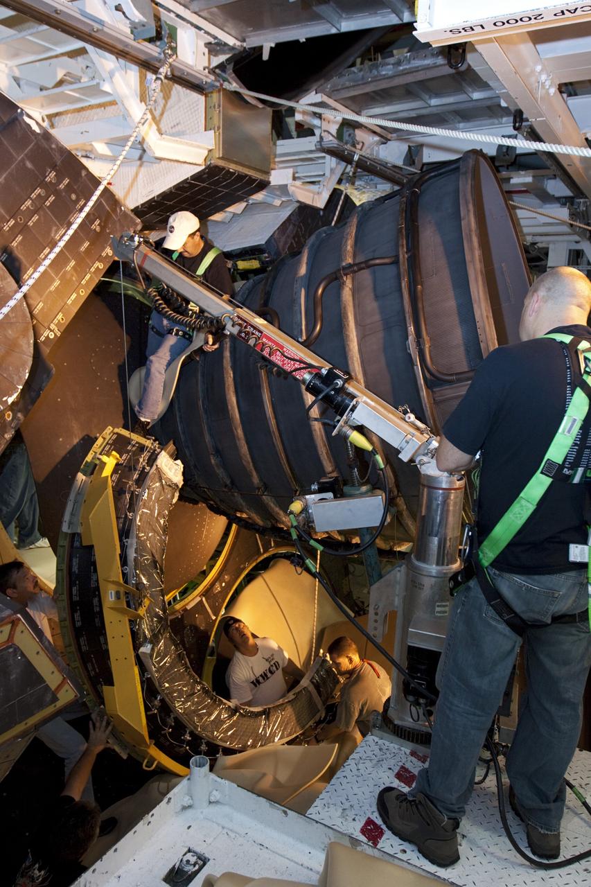 CAPE CANAVERAL, Fla. – Inside Orbiter Processing Facility-1 at NASA’s Kennedy Space Center in Florida, technicians help guide a dome heat shield for installation around one of space shuttle Discovery’s three replica shuttle main engines. The dome heat shields are composed of two, semi-circle-shaped sections of thermal protection system tiles that surround the engines. The work is part of the Space Shuttle Program’s transition and retirement processing of shuttle Discovery. Discovery is being prepared for display at the Smithsonian’s National Air and Space Museum, Steven F. Udvar-Hazy Center in Chantilly, Va. For more information, visit http://www.nasa.gov/shuttle. Photo credit: NASA/Kim Shiflett