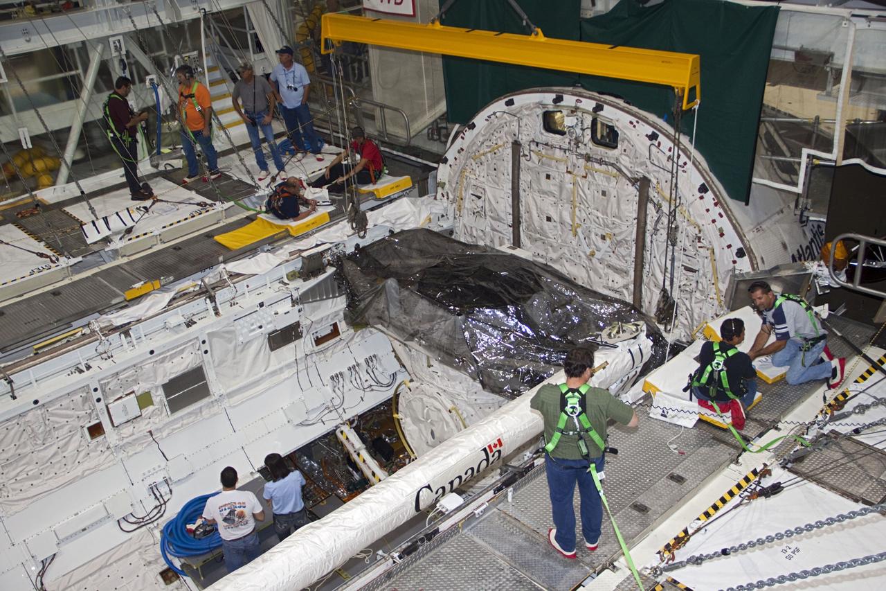 CAPE CANAVERAL, Fla. -- Workers prepare to remove the airlock from the cargo bay of space shuttle Atlantis in Orbiter Processing Facility-2 at NASA's Kennedy Space Center in Florida. The airlock was the connecting point between the shuttle and International Space Station. It was removed as part of the ongoing work to prepare the shuttles for public display. The shuttle is being prepared for display at the Kennedy Space Center Visitor Complex. Photo credit: NASA/Jim Grossmann