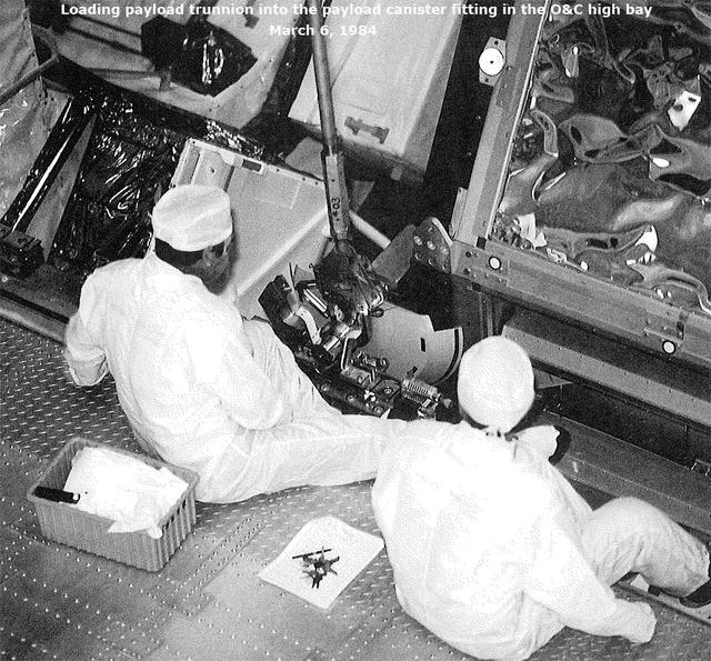 Loading payload trunnion into the payload canister fitting in the O&C high bay, March 6, 1984
