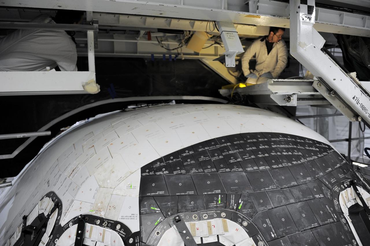 CAPE CANAVERAL, Fla. -- Inside Orbiter Processing Facility-2 at NASA’s Kennedy Space Center in Florida, technicians prepare space shuttle Atlantis for removal of the top emergency escape window.    The window is being removed in order to gain access to remove hazardous pyrotechnics from the shuttle. The window will be shipped to Johnson Space Center in Houston for inspections and a replacement outer pane will be installed in its place. The work is part of the Space Shuttle Program’s transition and retirement processing of shuttle Atlantis. The shuttle is being prepared for display at the Kennedy Space Center Visitor Complex in Florida.  Photo credit: NASA/Kim Shiflett