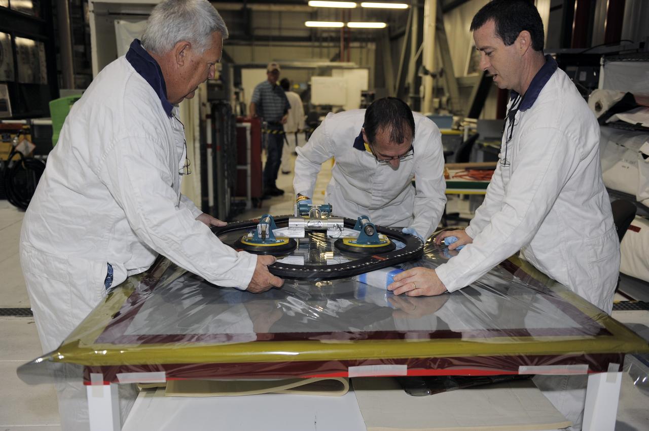 CAPE CANAVERAL, Fla. -- Inside Orbiter Processing Facility-2 at NASA’s Kennedy Space Center in Florida, technicians inspect the top emergency escape window that was removed from space shuttle Atlantis. The window is being removed in order to gain access to remove hazardous pyrotechnics from the shuttle. The window will be shipped to Johnson Space Center in Houston for inspections and a replacement outer pane will be installed in its place. The work is part of the Space Shuttle Program’s transition and retirement processing of shuttle Atlantis. The shuttle is being prepared for display at the Kennedy Space Center Visitor Complex in Florida. Photo credit: NASA/Kim Shiflett