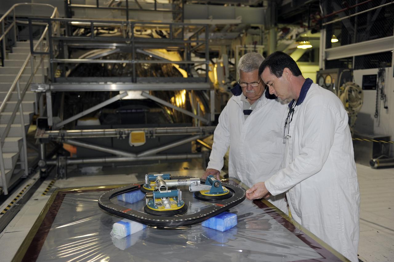 CAPE CANAVERAL, Fla. -- Inside Orbiter Processing Facility-2 at NASA’s Kennedy Space Center in Florida, technicians inspect the top emergency escape window that was removed from space shuttle Atlantis.    The window is being removed in order to gain access to remove hazardous pyrotechnics from the shuttle. The window will be shipped to Johnson Space Center in Houston for inspections and a replacement outer pane will be installed in its place. The work is part of the Space Shuttle Program’s transition and retirement processing of shuttle Atlantis. The shuttle is being prepared for display at the Kennedy Space Center Visitor Complex in Florida.  Photo credit: NASA/Kim Shiflett