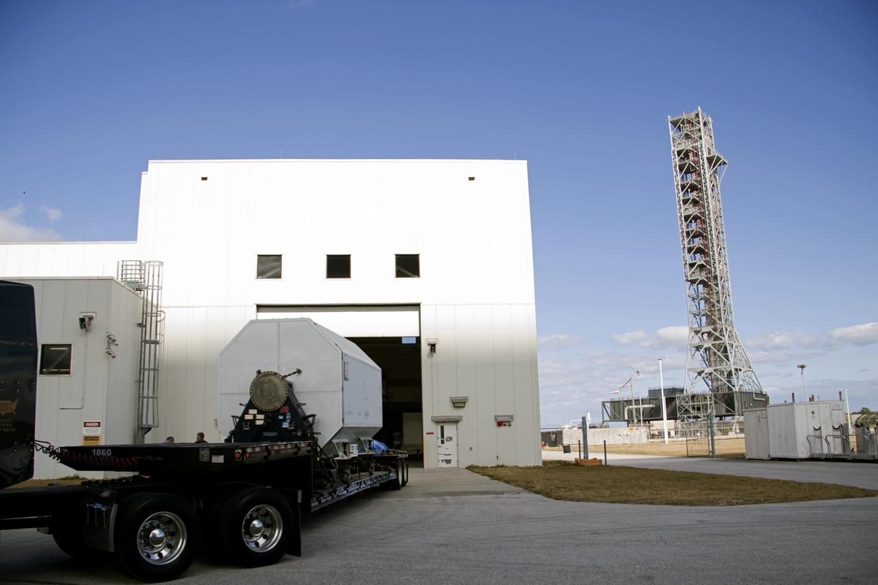 CAPE CANAVERAL, Fla. – At NASA’s Kennedy Space Center in Florida, a flatbed truck prepares to depart from the Space Shuttle Main Engine Processing Facility carrying a transportation canister containing a Pratt & Whitney Rocketdyne space shuttle main engine (SSME).  A right is NASA's new mobile launcher.    This is the second of the 15 engines used during the Space Shuttle Program to be transported to NASA's Stennis Space Center in Mississippi. The engines will be stored at Stennis for future use on NASA's new heavy-lift rocket, the Space Launch System (SLS), which will carry NASA's new Orion spacecraft, cargo, equipment and science experiments to space.  For more information, visit http://www.nasa.gov/shuttle.  Photo credit: NASA/Jim Grossmann