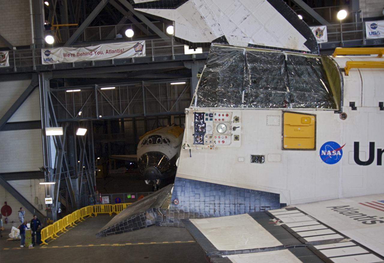 CAPE CANAVERAL, Fla. -- Space shuttle Endeavour (in the background) seems to proclaim "We're behind you, Atlantis" as space shuttle Atlantis rolls into the transfer aisle of the Vehicle Assembly Building (VAB) at NASA's Kennedy Space Center in Florida, following its move from Orbiter Processing Facility-2. Atlantis will be stored temporarily in the VAB while transition and retirement processing resumes on shuttle Endeavour in the processing hangar. Endeavour is being prepared for public display at the California Science Center in Los Angeles. A groundbreaking was held Jan. 18 for Atlantis' future home -- a 65,000-square-foot exhibit in Shuttle Plaza at the Kennedy Space Center Visitor Complex. For additional information, visit http://www.nasa.gov/shuttle. Photo credit: NASA/Jim Grossmann