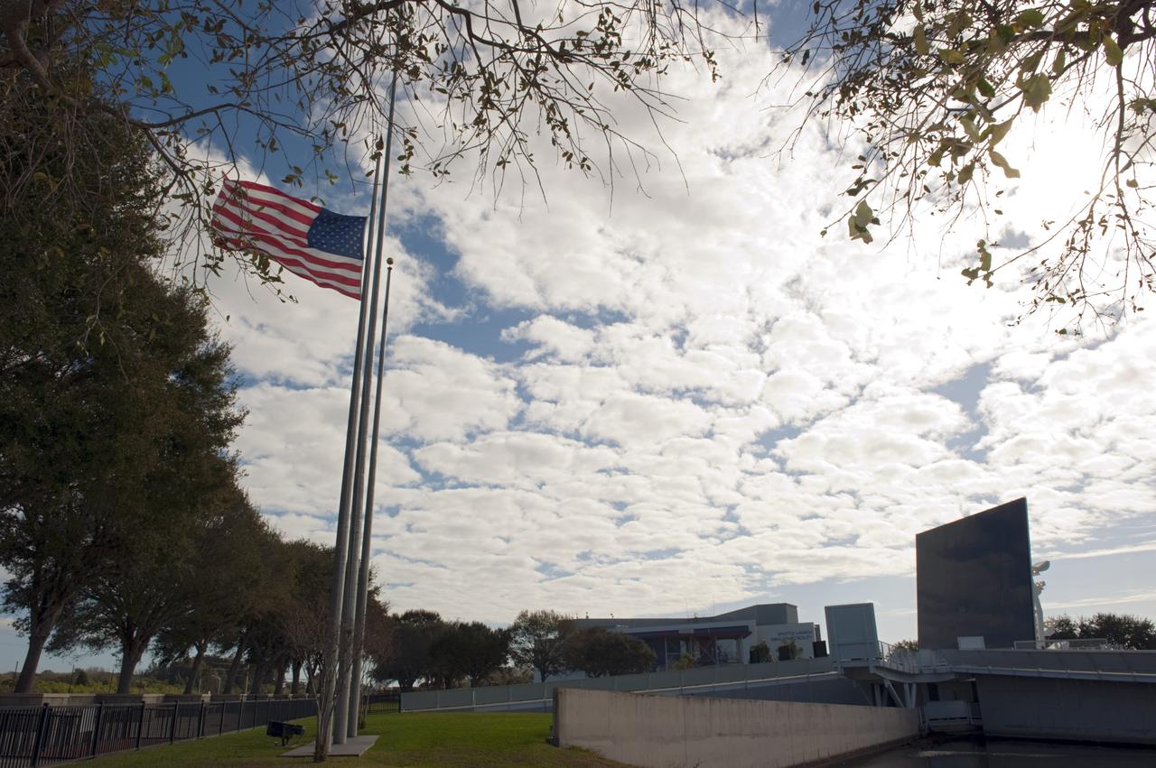 CAPE CANAVERAL, Fla. -- An American flag flies at half staff near the Space Mirror Memorial at the Kennedy Space Center Visitor Complex in Florida during Kennedy Space Center’s NASA Day of Remembrance.     The Day of Remembrance honors members of the NASA family who lost their lives while furthering the cause of exploration and discovery, including the astronaut crews of Apollo 1 and space shuttles Challenger and Columbia. Kennedy civil service and contractor employees, along with the general public, paid their respects throughout the day. The visitor complex provided flowers for visitors to place at the memorial. Photo credit: NASA/Kim Shiflett