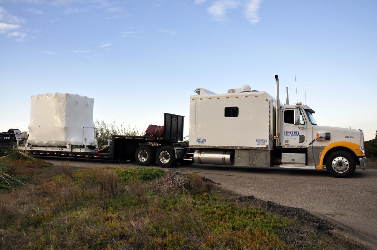 VANDENBERG AIR FORCE BASE, Calif. -- NASA's Nuclear Spectroscopic Telescope Array (NuSTAR), enclosed in an environmentally controlled shipping container, is trucked by trailer to processing facility 1555 at Vandenberg Air Force Base (VAFB) in California. The spacecraft arrived at 7:52 a.m. PST after a cross-country trip from Orbital Sciences' manufacturing plant in Dulles, Va., which began Jan. 24. The spacecraft will be offloaded into the processing hangar, joining the Pegasus XL rocket that is set to carry it to space. After NuSTAR is removed from its shipping container, checkout and other processing activity will begin. The spacecraft will be integrated with the Pegasus in mid-February and encapsulation in the vehicle fairing will follow. After processing is completed, the rocket and spacecraft will be flown on Orbital's L-1011 carrier aircraft to the Ronald Reagan Ballistic Missile Defense Test Site at the Pacific Ocean's Kwajalein Atoll for launch in March. The high-energy x-ray telescope will conduct a census for black holes, map radioactive material in young supernovae remnants, and study the origins of cosmic rays and the extreme physics around collapsed stars. For more information, visit http://www.nasa.gov/nustar. Photo credit: NASA/Randy Beaudoin, VAFB