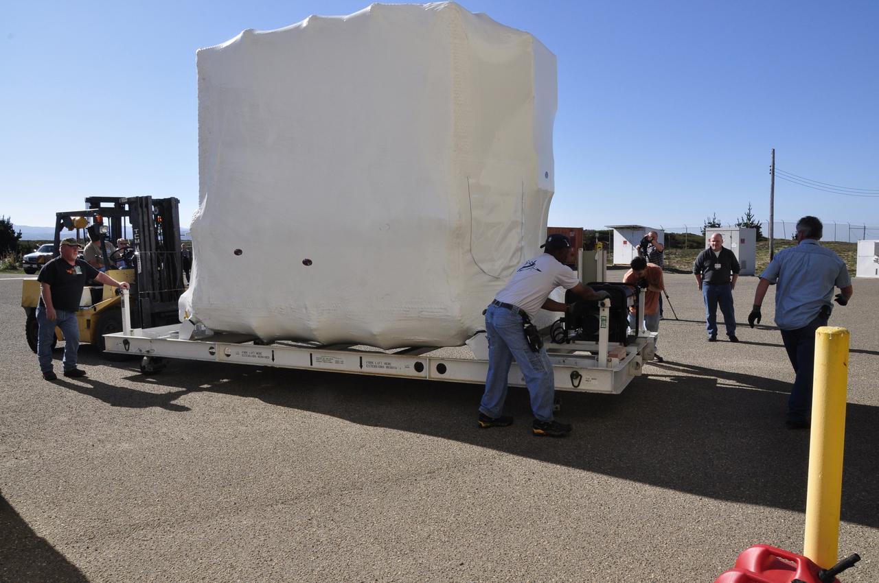 VANDENBERG AIR FORCE BASE, Calif. -- Workers position NASA's Nuclear Spectroscopic Telescope Array (NuSTAR), enclosed in an environmentally controlled shipping container, onto a payload transporter for transfer of the telescope into the airlock of processing facility 1555 at Vandenberg Air Force Base (VAFB) in California. The spacecraft arrived at 7:52 a.m. PST after a cross-country trip from Orbital Sciences' manufacturing plant in Dulles, Va., which began Jan. 24. The spacecraft will be offloaded into the processing hangar, joining the Pegasus XL rocket that is set to carry it to space. After NuSTAR is removed from its shipping container, checkout and other processing activity will begin. The spacecraft will be integrated with the Pegasus in mid-February and encapsulation in the vehicle fairing will follow. After processing is completed, the rocket and spacecraft will be flown on Orbital's L-1011 carrier aircraft to the Ronald Reagan Ballistic Missile Defense Test Site at the Pacific Ocean's Kwajalein Atoll for launch in March. The high-energy x-ray telescope will conduct a census for black holes, map radioactive material in young supernovae remnants, and study the origins of cosmic rays and the extreme physics around collapsed stars. For more information, visit http://www.nasa.gov/nustar. Photo credit: NASA/Randy Beaudoin, VAFB
