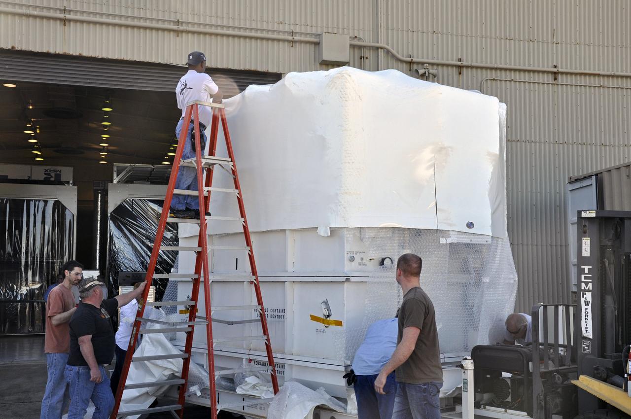 VANDENBERG AIR FORCE BASE, Calif. -- Workers unwrap the environmentally controlled shipping container enclosing NASA's Nuclear Spectroscopic Telescope Array (NuSTAR) in the airlock of processing facility 1555 at Vandenberg Air Force Base (VAFB) in California.    The spacecraft arrived at 7:52 a.m. PST after a cross-country trip from Orbital Sciences' manufacturing plant in Dulles, Va., which began Jan. 24. The spacecraft will be offloaded into the processing hangar, joining the Pegasus XL rocket that is set to carry it to space. After NuSTAR is removed from its shipping container, checkout and other processing activity will begin. The spacecraft will be integrated with the Pegasus in mid-February and encapsulation in the vehicle fairing will follow. After processing is completed, the rocket and spacecraft will be flown on Orbital's L-1011 carrier aircraft to the Ronald Reagan Ballistic Missile Defense Test Site at the Pacific Ocean's Kwajalein Atoll for launch in March.  The high-energy x-ray telescope will conduct a census for black holes, map radioactive material in young supernovae remnants, and study the origins of cosmic rays and the extreme physics around collapsed stars. For more information, visit http://www.nasa.gov/nustar. Photo credit: NASA/Randy Beaudoin, VAFB