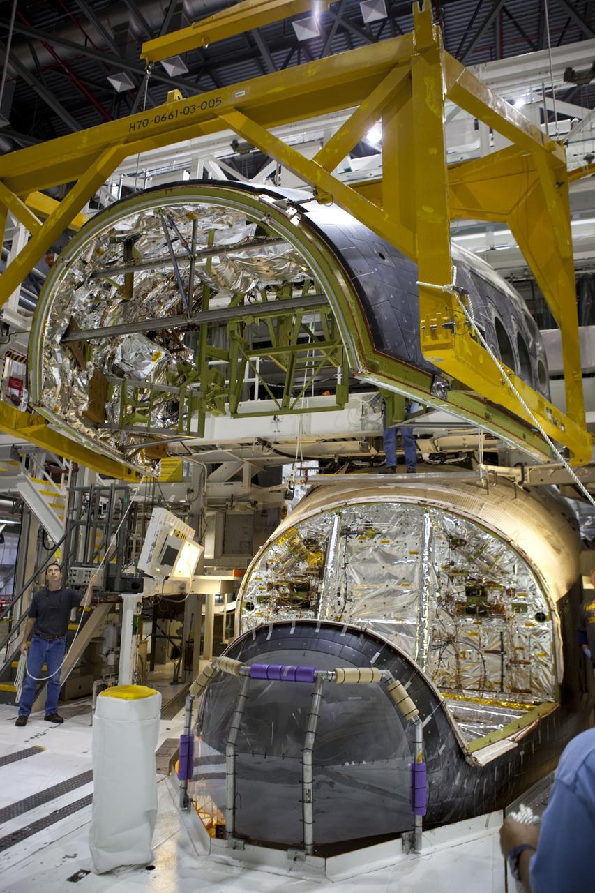 CAPE CANAVERAL, Fla. – In Orbiter Processing Facility-2 at NASA’s Kennedy Space Center in Florida, technicians monitor the progress as a large crane lifts and moves the forward reaction control system (FRCS) closer for installation on space shuttle Endeavour. The work is part of the Space Shuttle Program transition and retirement processing of Endeavour. The FRCS helped maneuver a shuttle while it was in orbit. The FRCS was removed from Endeavour and sent to White Sands Test Facility in N.M. to be cleaned of its toxic propellants. Endeavour is being prepared for display at the California Science Center in Los Angeles. Photo credit: NASA/Dimitri Gerondidakis