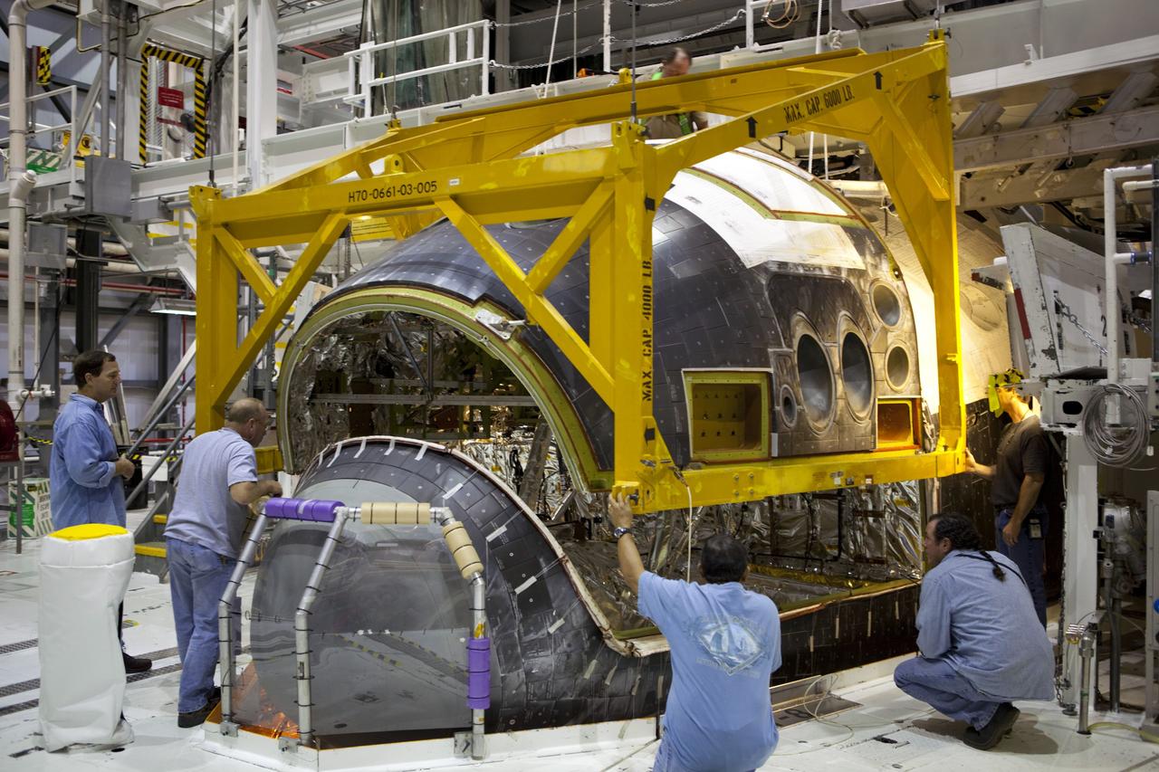 CAPE CANAVERAL, Fla. – In Orbiter Processing Facility-2 at NASA’s Kennedy Space Center in Florida, technicians help guide a large crane as it lowers the forward reaction control system (FRCS) for installation on space shuttle Endeavour. The work is part of the Space Shuttle Program transition and retirement processing of Endeavour. The FRCS helped maneuver a shuttle while it was in orbit. The FRCS was removed from Endeavour and sent to White Sands Test Facility in N.M. to be cleaned of its toxic propellants. Endeavour is being prepared for display at the California Science Center in Los Angeles. Photo credit: NASA/Dimitri Gerondidakis