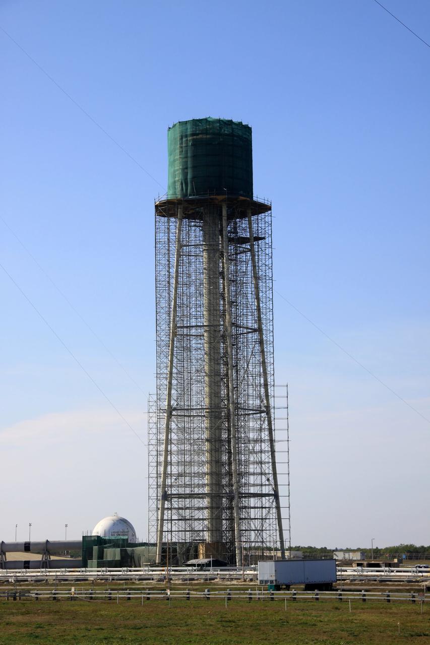CAPE CANAVERAL, Fla. - At NASA’s Kennedy Space Center in Florida, preparations are underway to sandblast and paint the 290-foot-high water tower at Launch Pad 39B. Scaffolding surrounds the tower and a special covering has been placed around the tank.    The water towers at Launch Complex 39, which includes pad A and B, were part of the sound suppression system used during space shuttle launches. Water stored in the 300,000-gallon tank would be released just prior to main engine ignition and flow by gravity to special mobile launcher platform (MLP) outlets. Nine seconds after shuttle liftoff, the peak flow rate was 900,000 gallons per minute and helped to protect the orbiter and payloads from being damaged by acoustical energy reflected from the MLP during liftoff. Photo Credit: NASA/Jim Grossmann