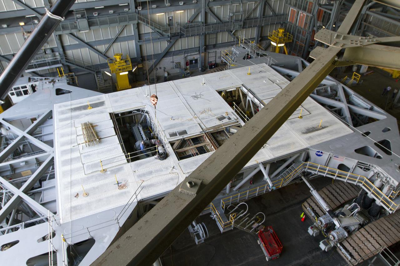 CAPE CANAVERAL, Fla. – Inside the Vehicle Assembly Building at NASA’s Kennedy Space Center in Florida, a crane is lowered toward crawler-transporter 2 CT-2) so that the Apollo era diesel engine can be removed. New engines will be installed later this month. Work is in progress in high bay 2 to upgrade CT-2 so that it can carry NASA’s Space Launch System heavy-lift rocket, which is under design, and new Orion spacecraft to the launch pad. The crawler-transporters were used to carry the mobile launcher platform and space shuttle to Launch Complex 39 for space shuttle launches for 30 years. Photo credit: NASA/Kim Shiflett