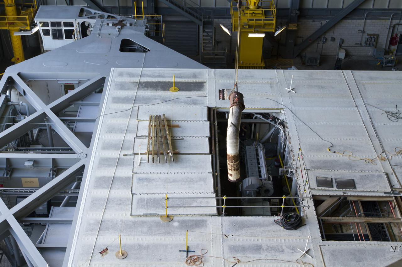 CAPE CANAVERAL, Fla. –– Inside the Vehicle Assembly Building at NASA’s Kennedy Space Center in Florida, a crane begins to lift part of an Apollo era diesel engine from crawler-transporter 2 CT-2). New engines will be installed later this month. Work is in progress in high bay 2 to upgrade CT-2 so that it can carry NASA’s Space Launch System heavy-lift rocket, which is under design, and new Orion spacecraft to the launch pad. The crawler-transporters were used to carry the mobile launcher platform and space shuttle to Launch Complex 39 for space shuttle launches for 30 years. Photo credit: NASA/Kim Shiflett