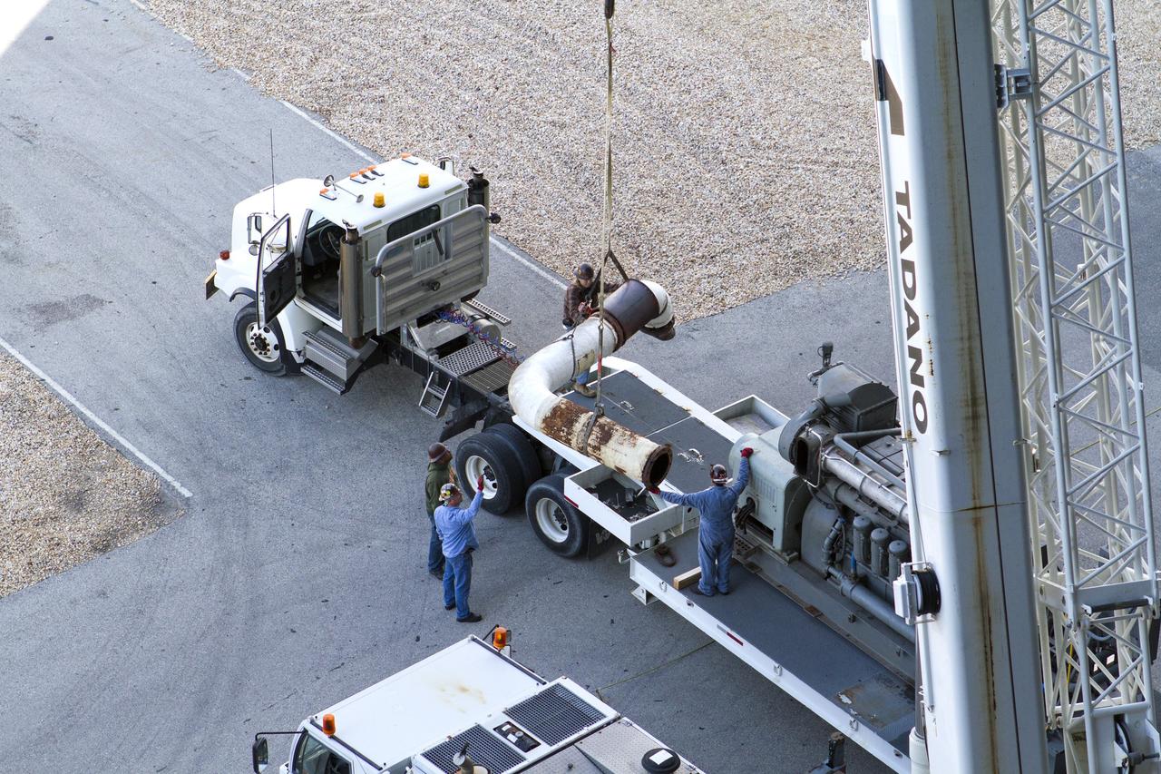 CAPE CANAVERAL, Fla. ––– Outside the Vehicle Assembly Building at NASA’s Kennedy Space Center in Florida, a crane is used to lower part of an Apollo era diesel engine from crawler-transporter 2 CT-2) onto the flatbed of a truck. New engines will be installed later this month. Work is in progress in high bay 2 to upgrade CT-2 so that it can carry NASA’s Space Launch System heavy-lift rocket, which is under design, and new Orion spacecraft to the launch pad. The crawler-transporters were used to carry the mobile launcher platform and space shuttle to Launch Complex 39 for space shuttle launches for 30 years. Photo credit: NASA/Kim Shiflett