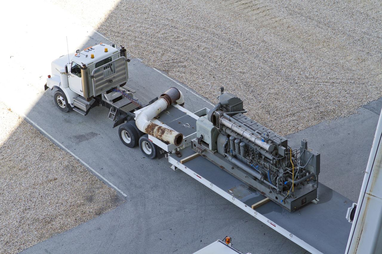 CAPE CANAVERAL, Fla. –– Outside the Vehicle Assembly Building at NASA’s Kennedy Space Center in Florida, a crane is used to lower part of an Apollo era diesel engine from crawler-transporter 2 CT-2) onto the flatbed of a truck. New engines will be installed later this month. Work is in progress in high bay 2 to upgrade CT-2 so that it can carry NASA’s Space Launch System heavy-lift rocket, which is under design, and new Orion spacecraft to the launch pad. The crawler-transporters were used to carry the mobile launcher platform and space shuttle to Launch Complex 39 for space shuttle launches for 30 years. Photo credit: NASA/Kim Shiflett