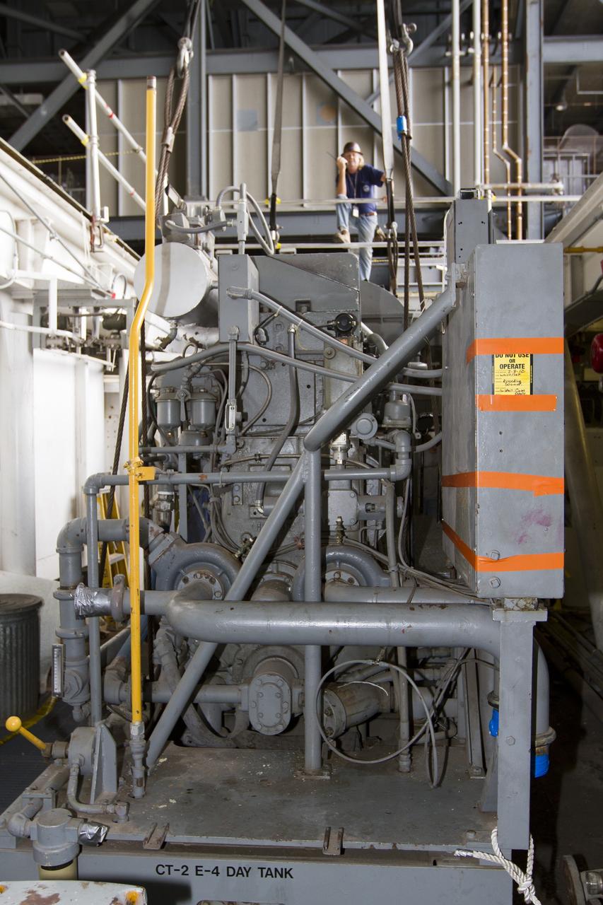 CAPE CANAVERAL, Fla. ––Inside the Vehicle Assembly Building at NASA’s Kennedy Space Center in Florida, a technician monitors the progress as a crane begins to lift an Apollo era diesel engine from crawler-transporter 2 CT-2). New engines will be installed later this month. Work is in progress in high bay 2 to upgrade CT-2 so that it can carry NASA’s Space Launch System heavy-lift rocket, which is under design, and new Orion spacecraft to the launch pad. The crawler-transporters were used to carry the mobile launcher platform and space shuttle to Launch Complex 39 for space shuttle launches for 30 years. Photo credit: NASA/Kim Shiflett