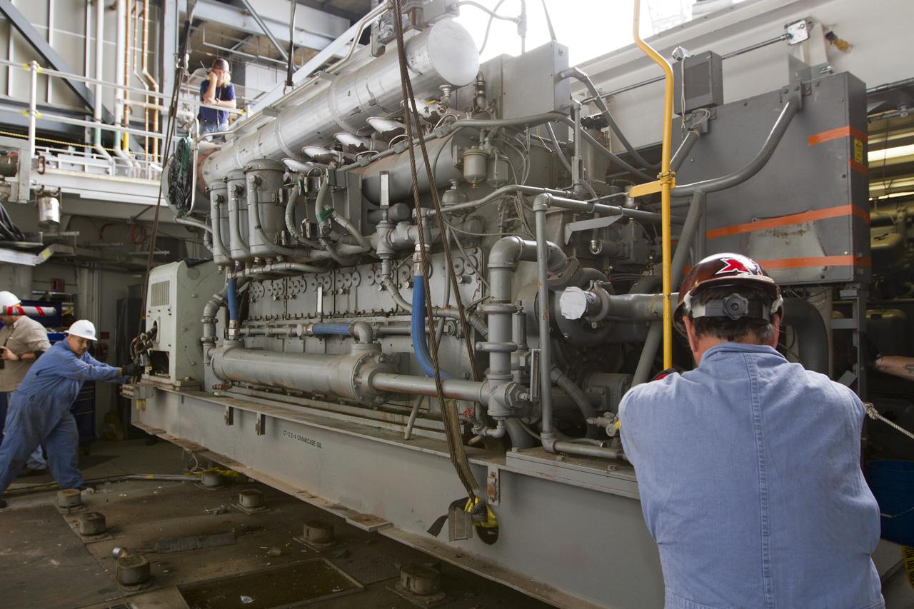 CAPE CANAVERAL, Fla. –– Inside the Vehicle Assembly Building at NASA’s Kennedy Space Center in Florida, technicians prepare an Apollo era diesel engine to be lifted by crane from crawler-transporter 2 CT-2). New engines will be installed later this month. Work is in progress in high bay 2 to upgrade CT-2 so that it can carry NASA’s Space Launch System heavy-lift rocket, which is under design, and new Orion spacecraft to the launch pad. The crawler-transporters were used to carry the mobile launcher platform and space shuttle to Launch Complex 39 for space shuttle launches for 30 years. Photo credit: NASA/Kim Shiflett