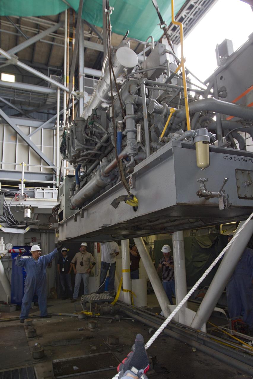 CAPE CANAVERAL, Fla. –– Inside the Vehicle Assembly Building at NASA’s Kennedy Space Center in Florida, technicians monitor the progress as a crane begins to lift an Apollo era diesel engine from crawler-transporter 2 CT-2). New engines will be installed later this month. Work is in progress in high bay 2 to upgrade CT-2 so that it can carry NASA’s Space Launch System heavy-lift rocket, which is under design, and new Orion spacecraft to the launch pad. The crawler-transporters were used to carry the mobile launcher platform and space shuttle to Launch Complex 39 for space shuttle launches for 30 years. Photo credit: NASA/Kim Shiflett
