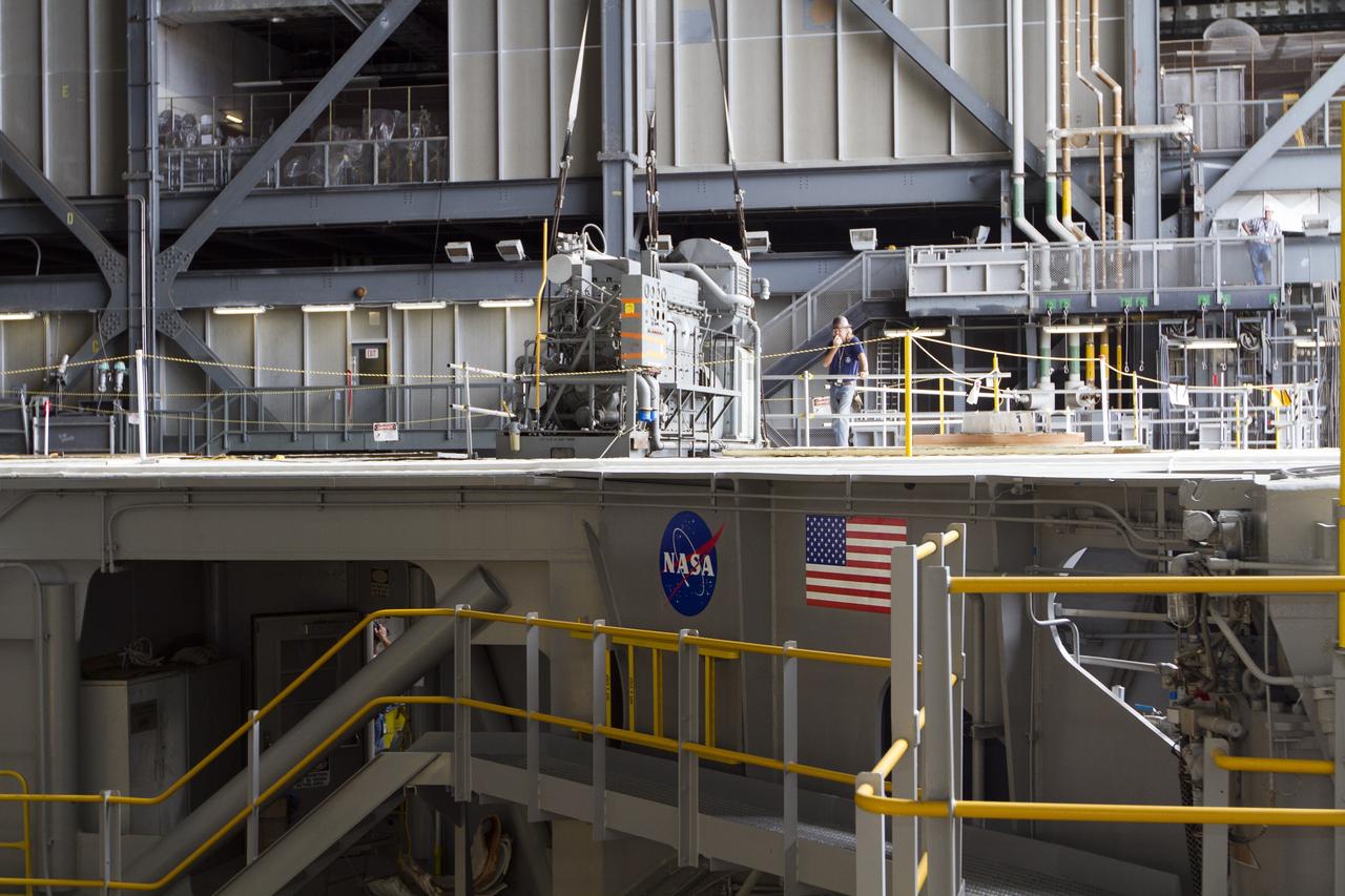 CAPE CANAVERAL, Fla. –– Inside the Vehicle Assembly Building at NASA’s Kennedy Space Center in Florida, technicians monitor the progress as a crane lifts an Apollo era diesel engine from crawler-transporter 2 CT-2). New engines will be installed later this month. Work is in progress in high bay 2 to upgrade CT-2 so that it can carry NASA’s Space Launch System heavy-lift rocket, which is under design, and new Orion spacecraft to the launch pad. The crawler-transporters were used to carry the mobile launcher platform and space shuttle to Launch Complex 39 for space shuttle launches for 30 years. Photo credit: NASA/Kim Shiflett