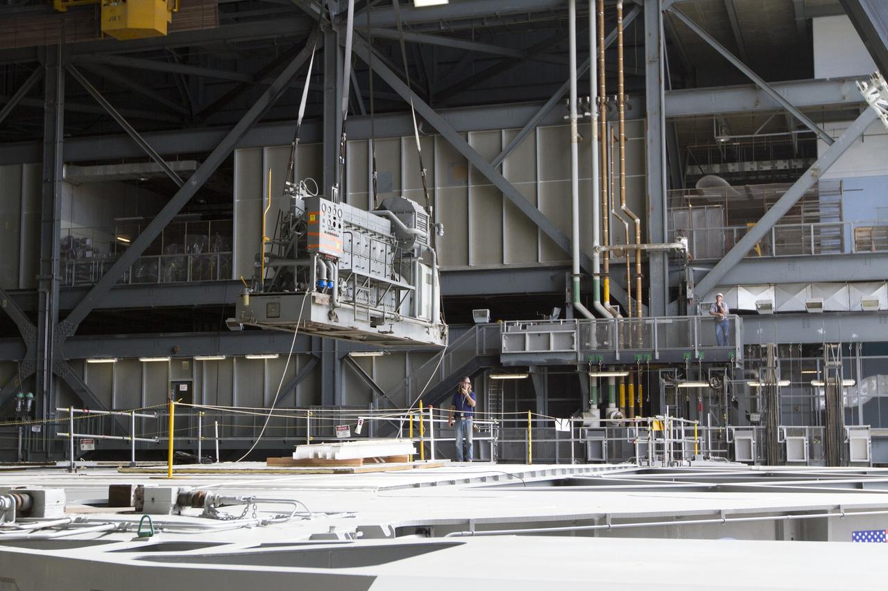 CAPE CANAVERAL, Fla. –– Inside the Vehicle Assembly Building at NASA’s Kennedy Space Center in Florida, a technician monitors the progress as a crane lifts an Apollo era diesel engine from crawler-transporter 2 CT-2). New engines will be installed later this month. Work is in progress in high bay 2 to upgrade CT-2 so that it can carry NASA’s Space Launch System heavy-lift rocket, which is under design, and new Orion spacecraft to the launch pad. The crawler-transporters were used to carry the mobile launcher platform and space shuttle to Launch Complex 39 for space shuttle launches for 30 years. Photo credit: NASA/Kim Shiflett