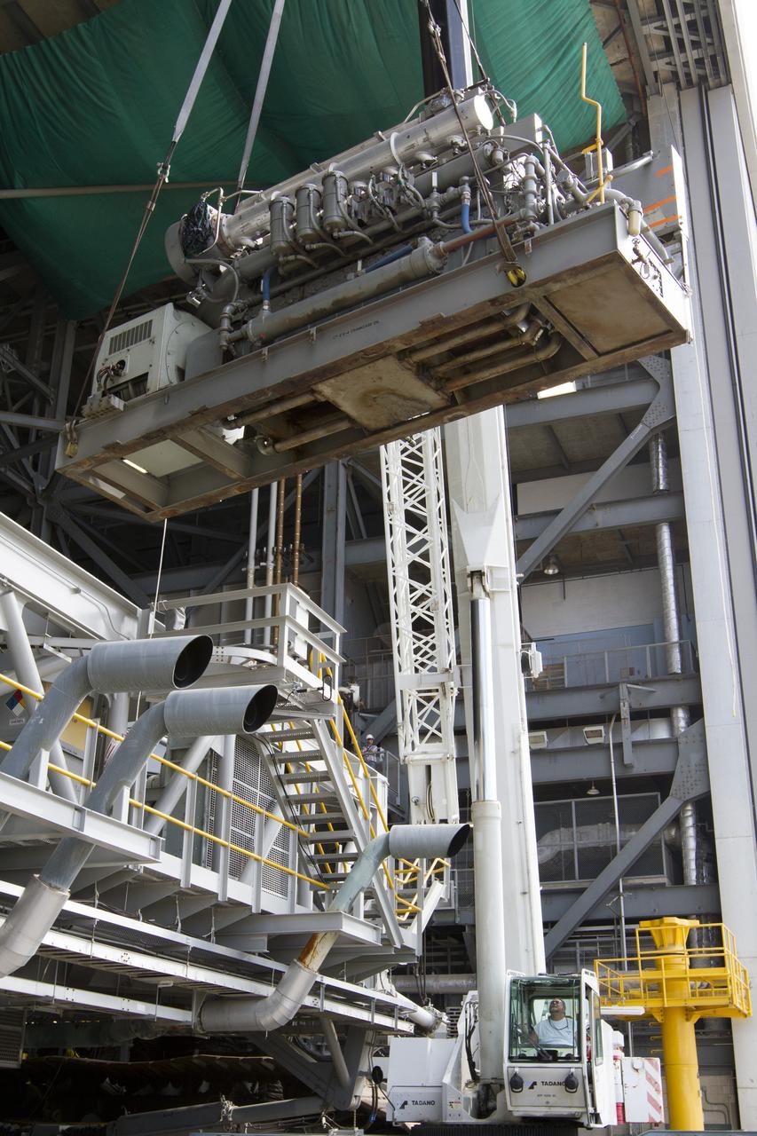 CAPE CANAVERAL, Fla. –– Inside the Vehicle Assembly Building at NASA’s Kennedy Space Center in Florida, a crane is used to lift an Apollo era diesel engine away from crawler-transporter 2 CT-2). New engines will be installed later this month. Work is in progress in high bay 2 to upgrade CT-2 so that it can carry NASA’s Space Launch System heavy-lift rocket, which is under design, and new Orion spacecraft to the launch pad. The crawler-transporters were used to carry the mobile launcher platform and space shuttle to Launch Complex 39 for space shuttle launches for 30 years. Photo credit: NASA/Kim Shiflett