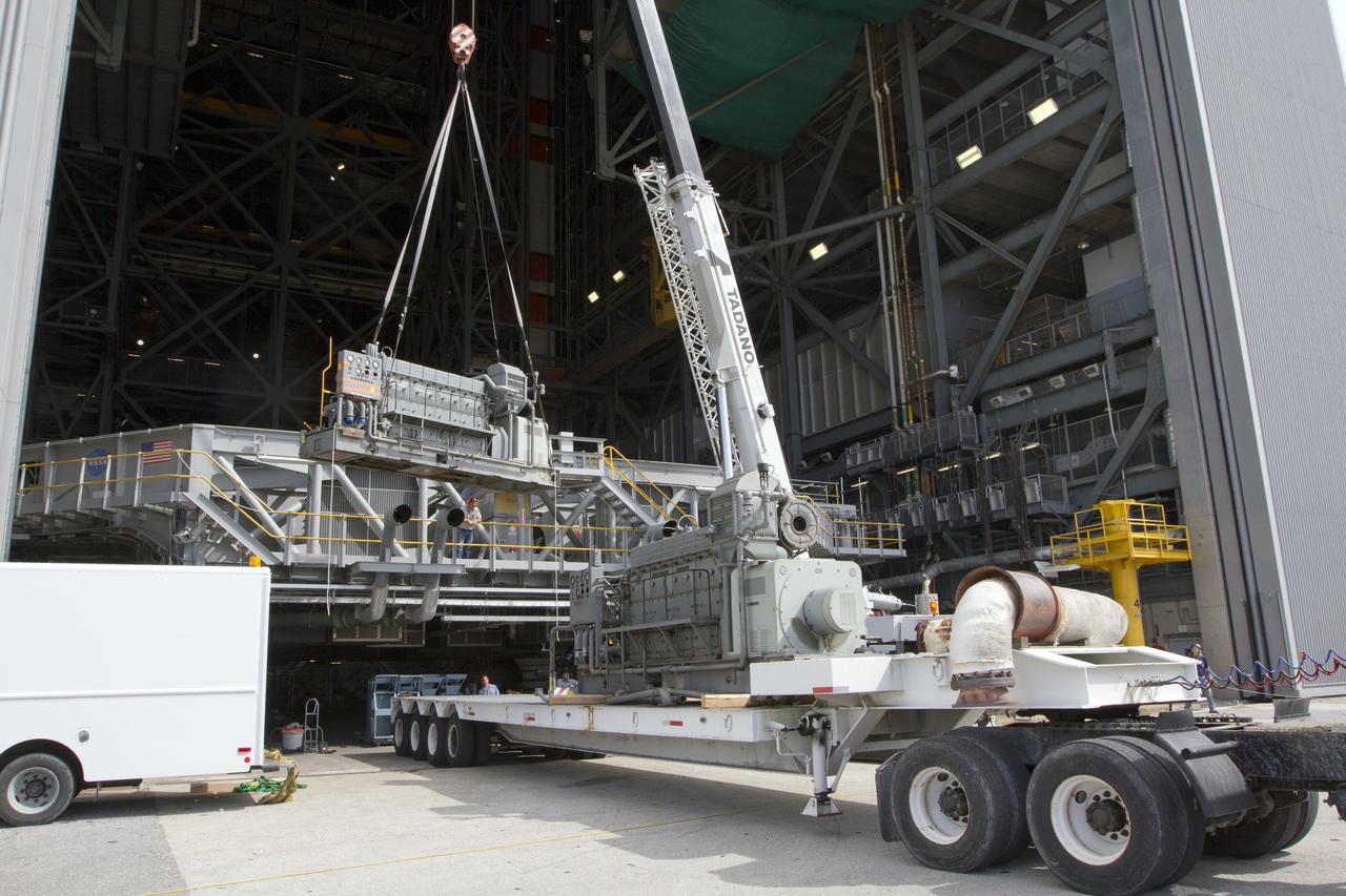 CAPE CANAVERAL, Fla. –– Just outside of the Vehicle Assembly Building at NASA’s Kennedy Space Center in Florida, a crane is used to lift an Apollo era diesel engine away from crawler-transporter 2 CT-2). New engines will be installed later this month. Work is in progress in high bay 2 to upgrade CT-2 so that it can carry NASA’s Space Launch System heavy-lift rocket, which is under design, and new Orion spacecraft to the launch pad. The crawler-transporters were used to carry the mobile launcher platform and space shuttle to Launch Complex 39 for space shuttle launches for 30 years. Photo credit: NASA/Kim Shiflett