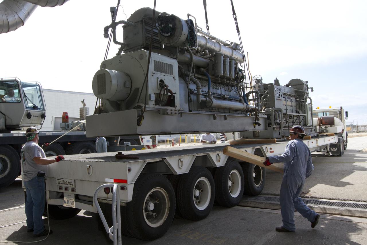 CAPE CANAVERAL, Fla. –– Just outside of the Vehicle Assembly Building at NASA’s Kennedy Space Center in Florida, technicians assist as a crane is used to lower an Apollo era diesel engine onto the flatbed of a truck after it was removed from crawler-transporter 2 CT-2). New engines will be installed later this month. Work is in progress in high bay 2 to upgrade CT-2 so that it can carry NASA’s Space Launch System heavy-lift rocket, which is under design, and new Orion spacecraft to the launch pad. The crawler-transporters were used to carry the mobile launcher platform and space shuttle to Launch Complex 39 for space shuttle launches for 30 years. Photo credit: NASA/Kim Shiflett