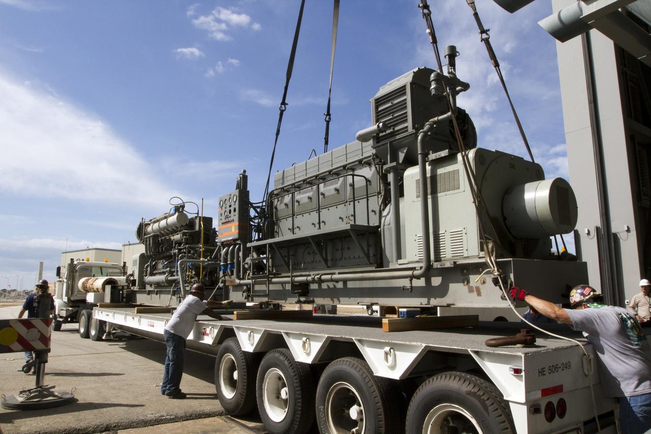 CAPE CANAVERAL, Fla. –– Just outside of the Vehicle Assembly Building at NASA’s Kennedy Space Center in Florida, technicians assist as a crane is used to lower an Apollo era diesel engine onto the flatbed of a truck after it was removed from crawler-transporter 2 CT-2). New engines will be installed later this month. Work is in progress in high bay 2 to upgrade CT-2 so that it can carry NASA’s Space Launch System heavy-lift rocket, which is under design, and new Orion spacecraft to the launch pad. The crawler-transporters were used to carry the mobile launcher platform and space shuttle to Launch Complex 39 for space shuttle launches for 30 years. Photo credit: NASA/Kim Shiflett