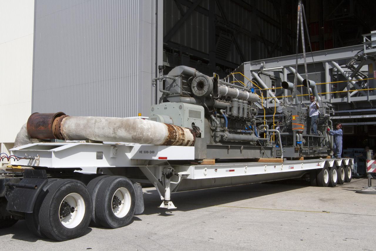 CAPE CANAVERAL, Fla. –– Just outside of the Vehicle Assembly Building at NASA’s Kennedy Space Center in Florida, technicians help secure an Apollo era diesel engine onto the flatbed of a truck after it was removed from crawler-transporter 2 CT-2). New engines will be installed later this month. Work is in progress in high bay 2 to upgrade CT-2 so that it can carry NASA’s Space Launch System heavy-lift rocket, which is under design, and new Orion spacecraft to the launch pad. The crawler-transporters were used to carry the mobile launcher platform and space shuttle to Launch Complex 39 for space shuttle launches for 30 years. Photo credit: NASA/Kim Shiflett