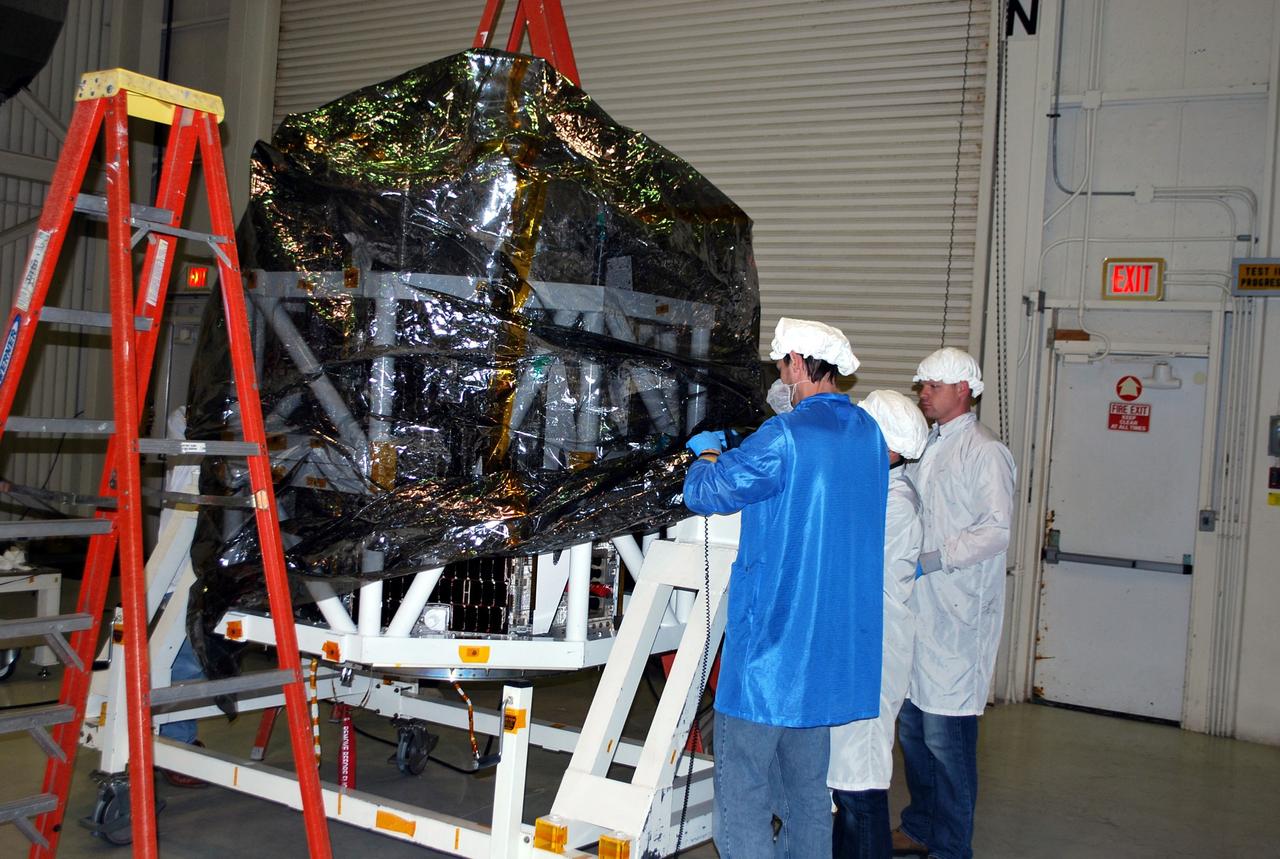 VANDENBERG AIR FORCE BASE, Calif. -- Technicians pull a protective plastic cover over NASA's NuSTAR spacecraft and the tilt-rotation fixture inside Orbital Sciences' processing facility at Vandenberg Air Force Base, Calif. The spacecraft will be rotated to horizontal for joining with the Pegasus XL rocket. The Orbital Sciences Pegasus will launch NASA's Nuclear Spectroscopic Telescope Array NuSTAR into space. After the rocket and spacecraft are processed at Vandenberg, they will be flown on Orbital's L-1011 carrier aircraft to the Ronald Reagan Ballistic Missile Defense Test Site at the Pacific Ocean’s Kwajalein Atoll for launch. The high-energy x-ray telescope will conduct a census for black holes, map radioactive material in young supernovae remnants, and study the origins of cosmic rays and the extreme physics around collapsed stars. For more information, visit science.nasa.gov/missions/nustar/. Photo credit: NASA/Randy Beaudoin, VAFB